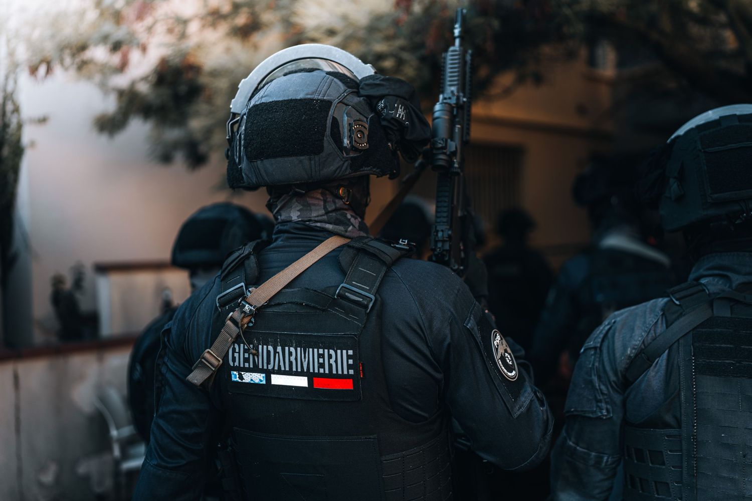 French Gendarmerie tactical unit in black gear assembled outside building during operation.