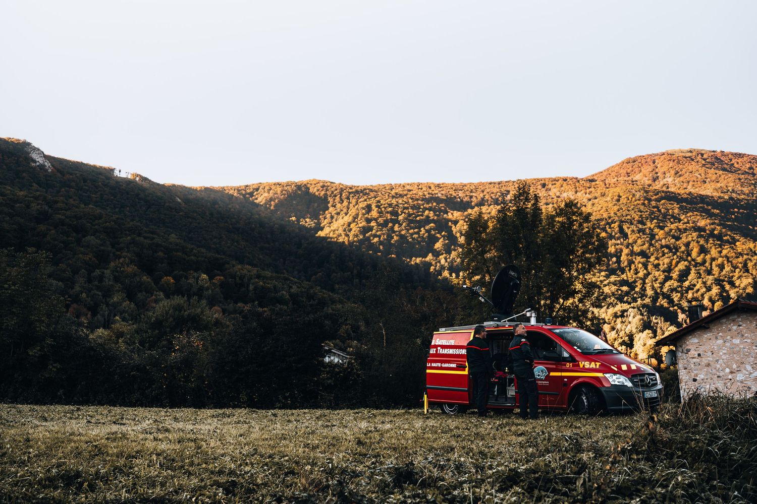 Red French fire department van parked in scenic autumn mountain valley landscape.
