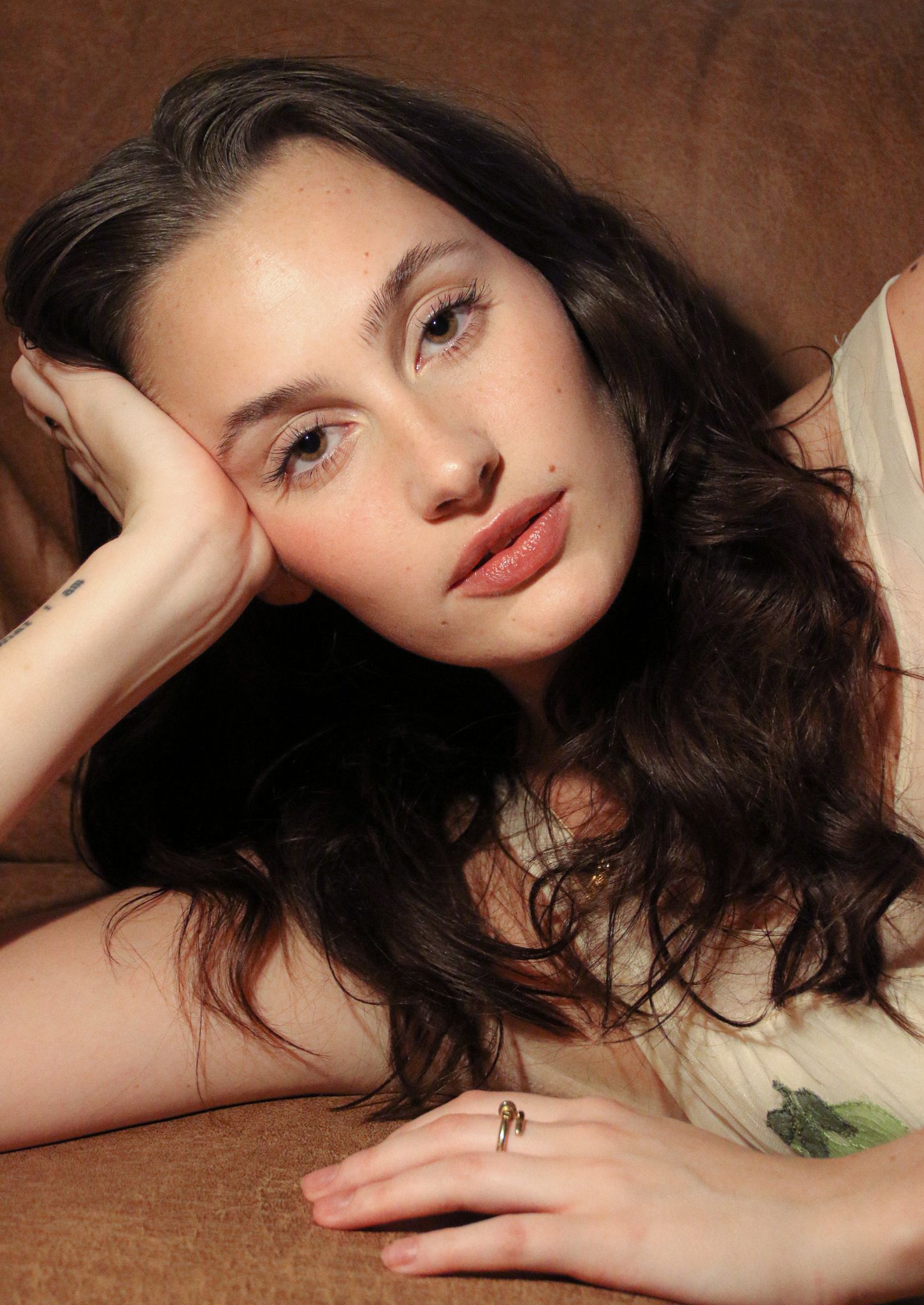 Brunette woman resting on a brown couch with a delicate ring.