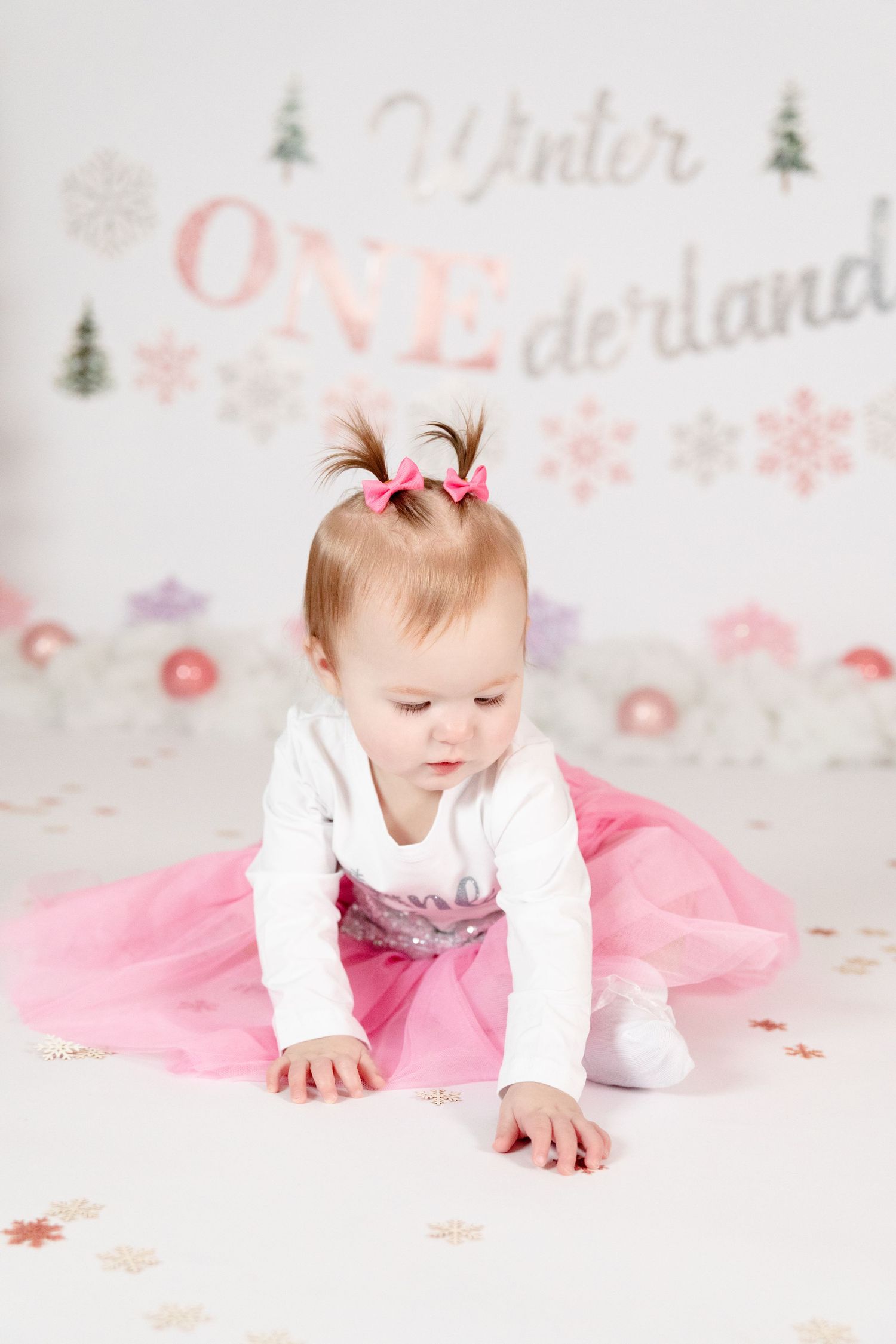 Infant girl in pink tutu crawling on floor at Winter ONEderland first birthday photo session.