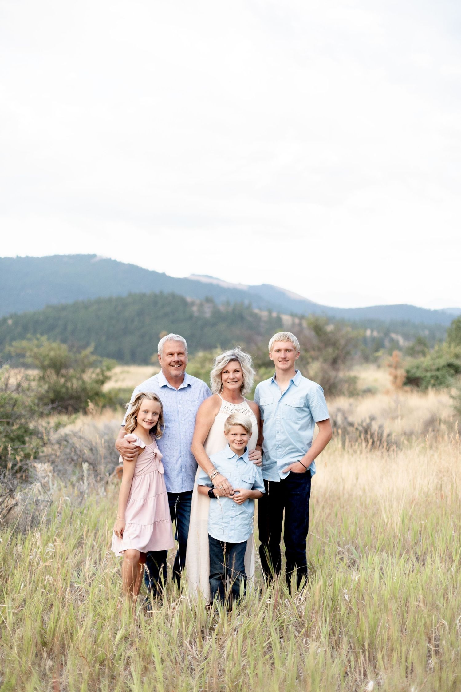 Family of five posing in a mountain meadow with grandparents, parents, and young children.