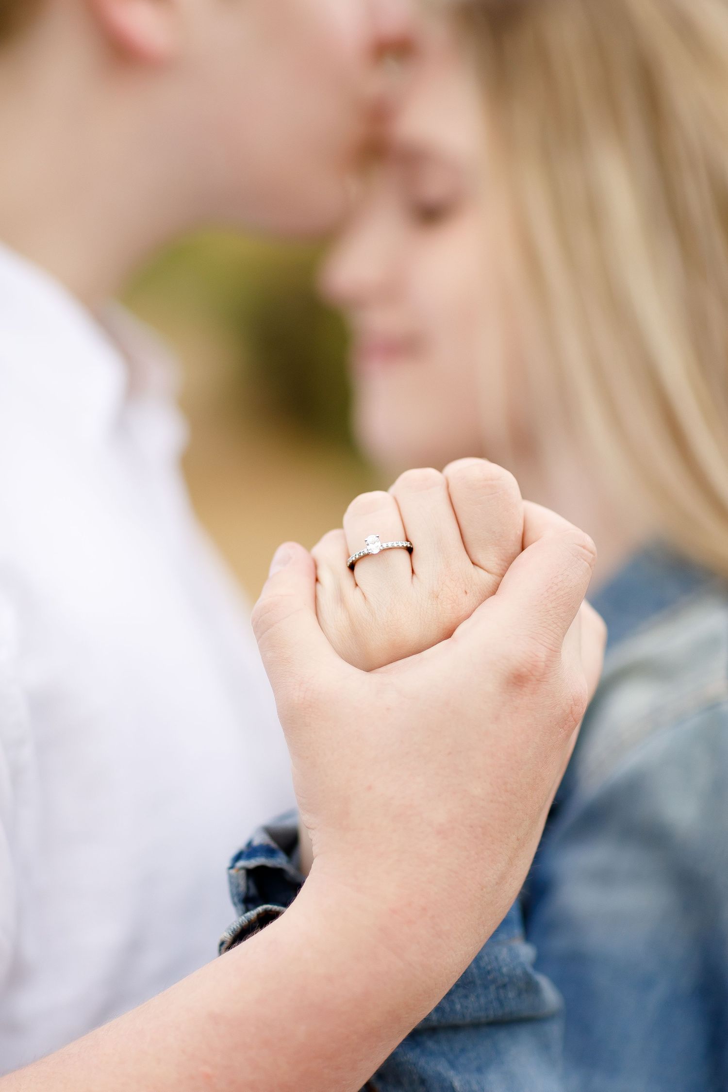 Close-up of an engaged couples clasped hands showing a sparkling diamond engagement ring.