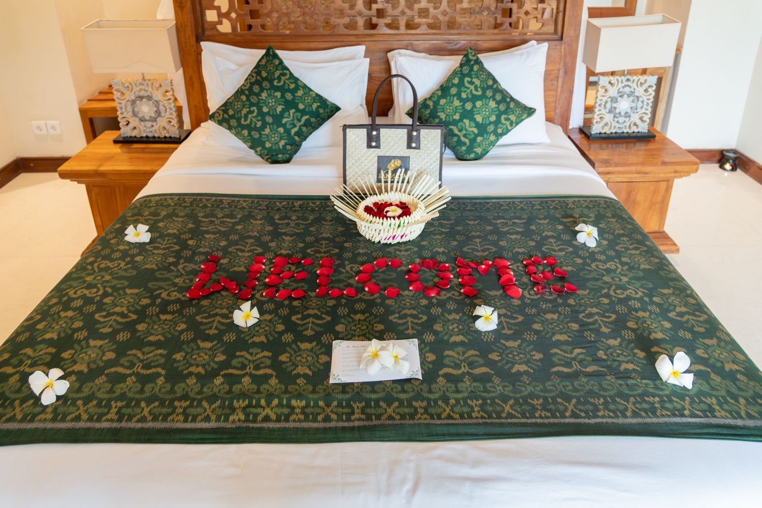 Flower petal welcome message arranged on a bed in a resort room.