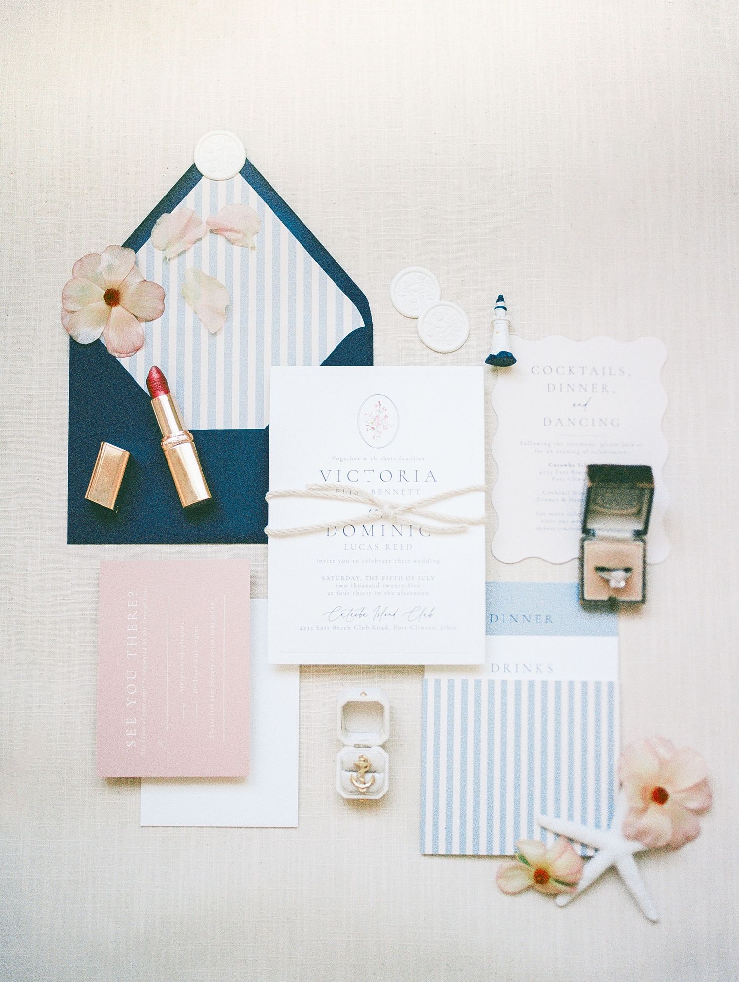 Elegant wedding invitation suite with navy blue envelope, blush pink accents, gold lipstick, floral details, and a vintage ring box.