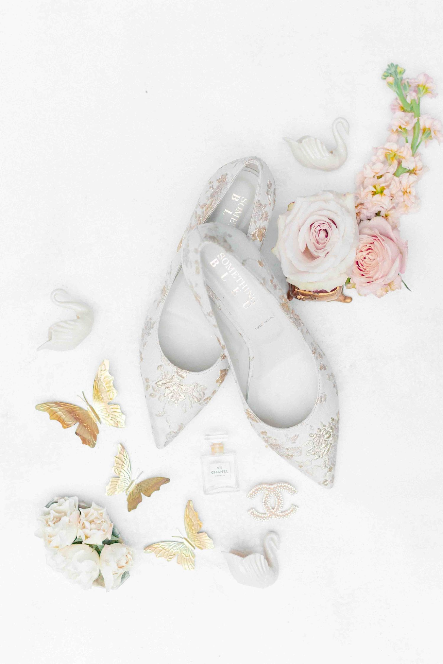 Elegant flat wedding shoes with floral embroidery styled with roses, Chanel perfume, and gold butterflies.