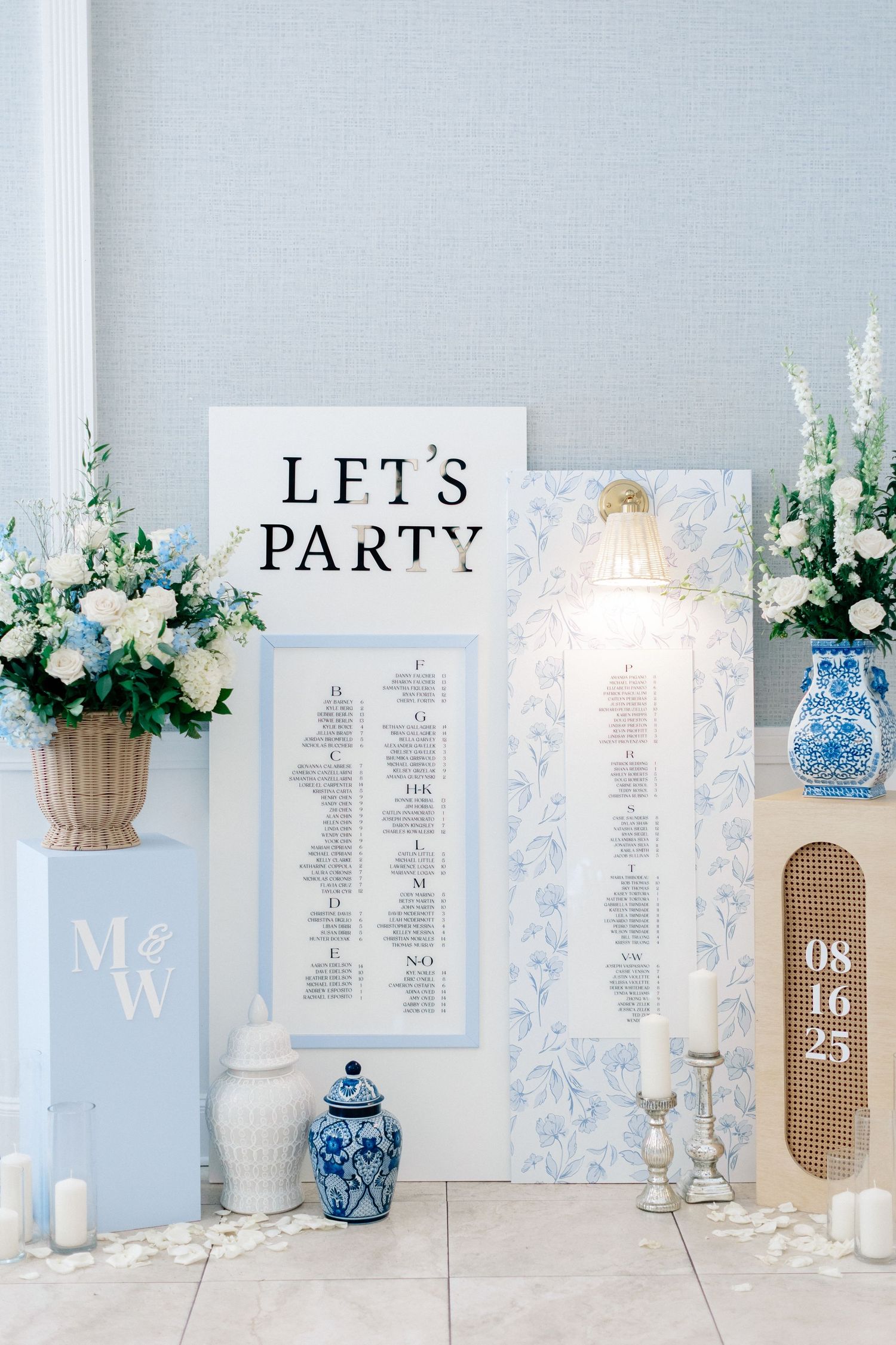 Elegant blue and white wedding reception decor with floral arrangements, seating chart, and a 