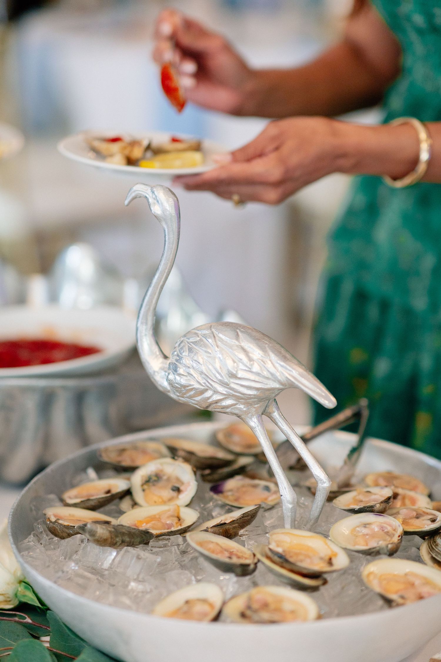 Silver flamingo figurine centerpiece on ice tray of fresh oysters at elegant seafood buffet display.