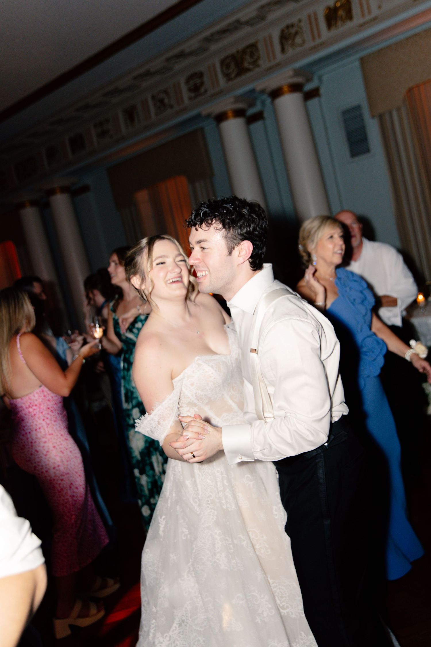 A bride and groom share a romantic dance together at their elegant wedding reception surrounded by guests.