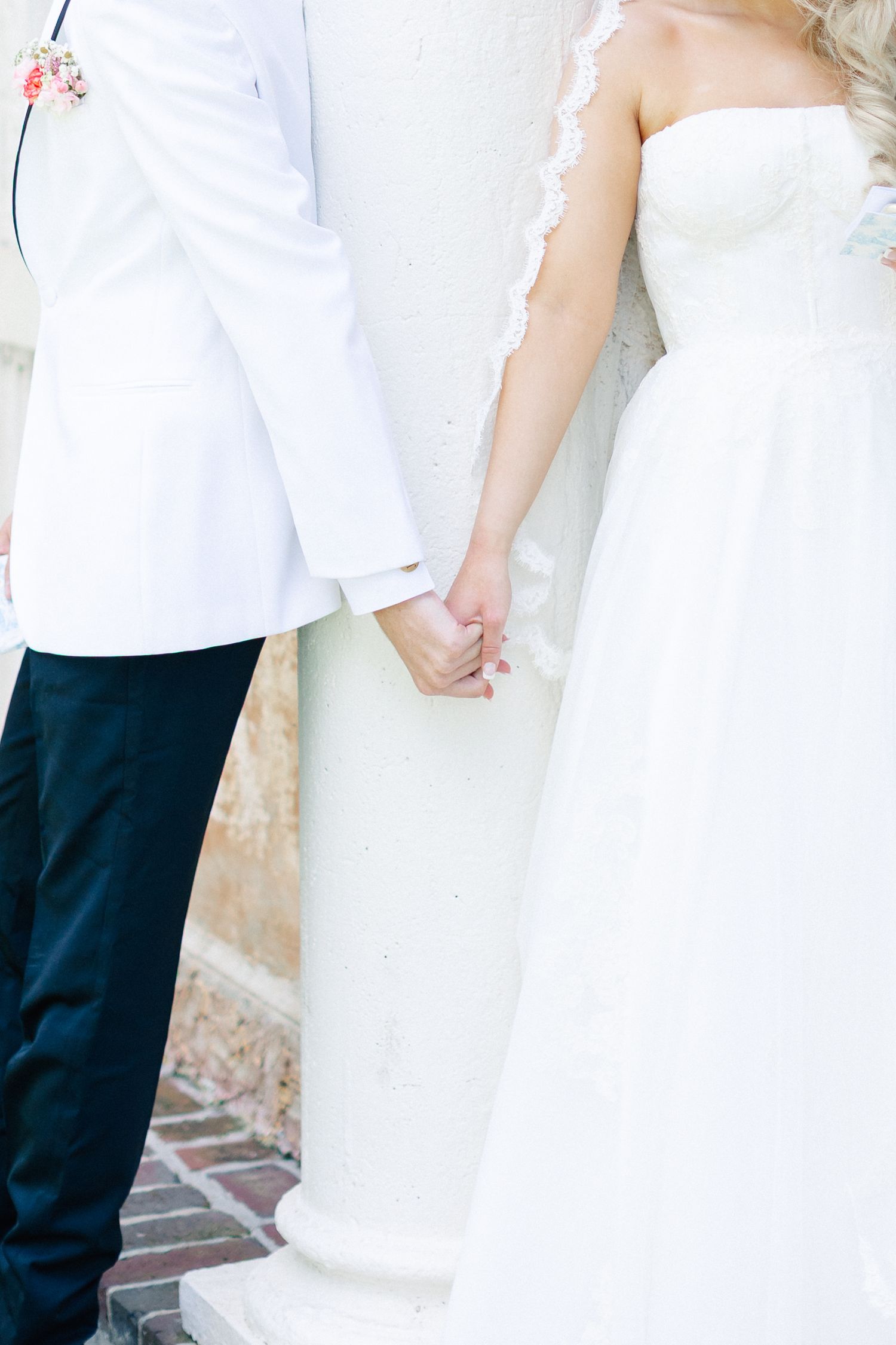 Bride and groom holding hands in wedding attire, white dress and white jacket with navy pants,wedding at Bella Cosa