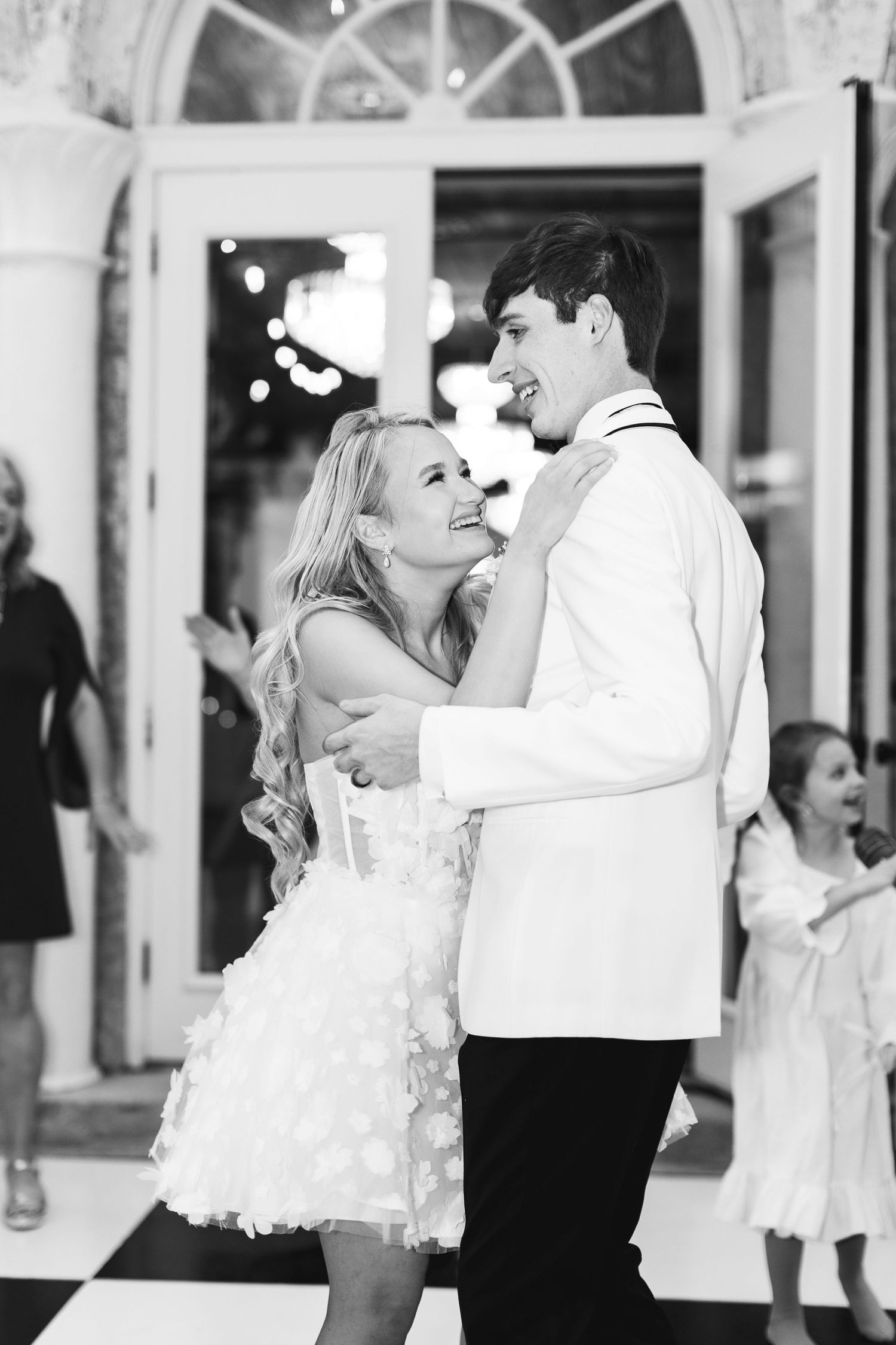 Black and white photo of a smiling couple sharing their first dance at a wedding reception, wedding at Bella Cosa