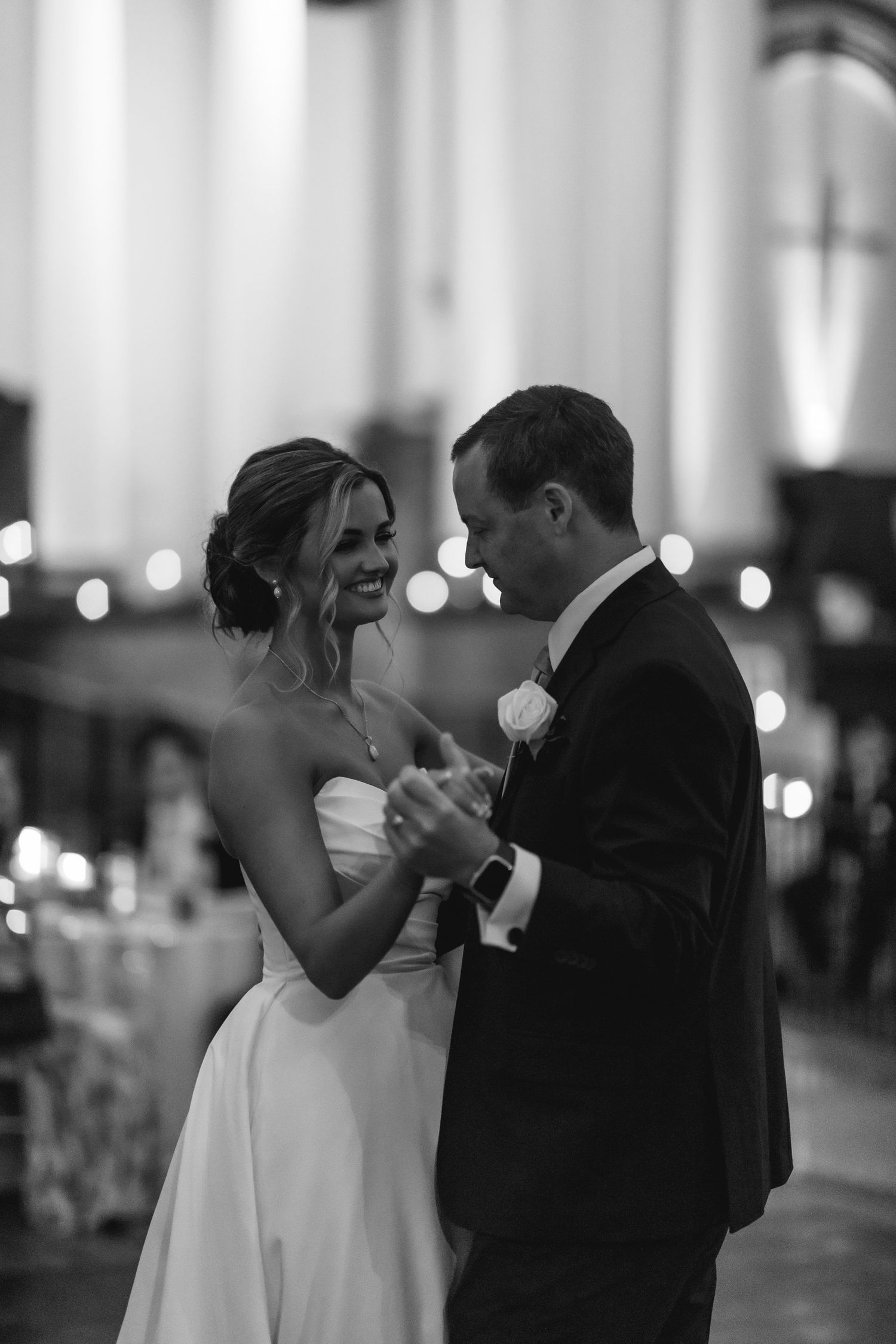 Black and white photo of a bride and groom sharing their first dance at a wedding reception.