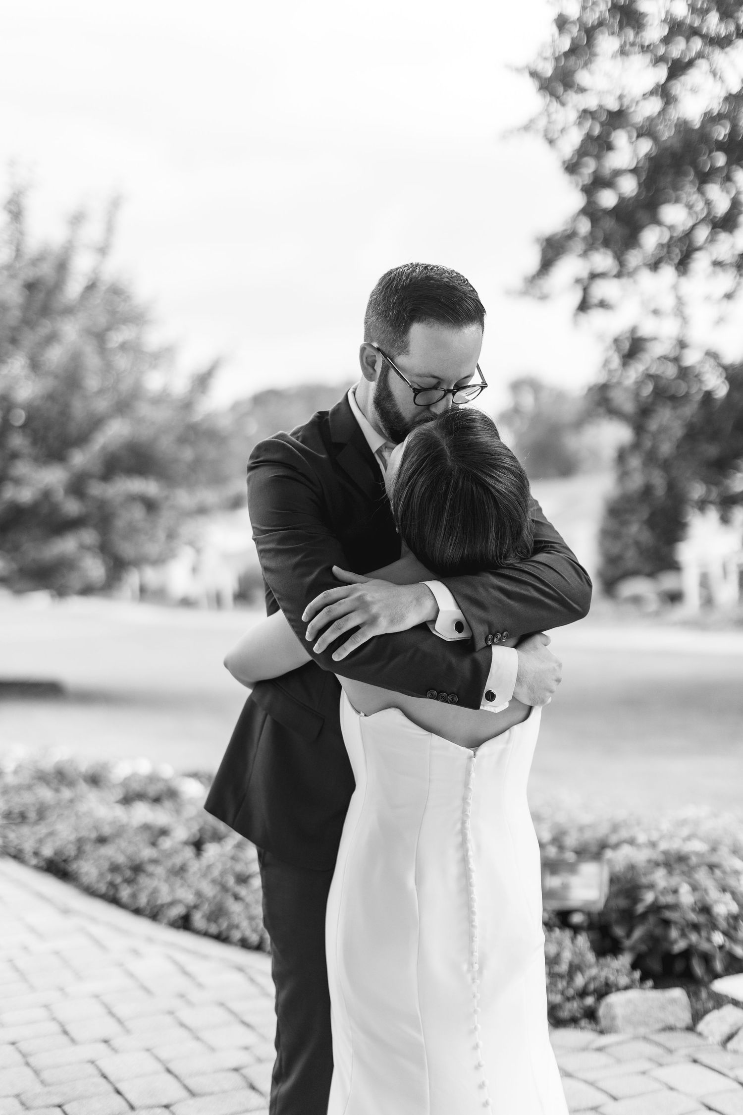 Black and white photo of a bride and groom sharing a tender embrace outdoors on their wedding day.