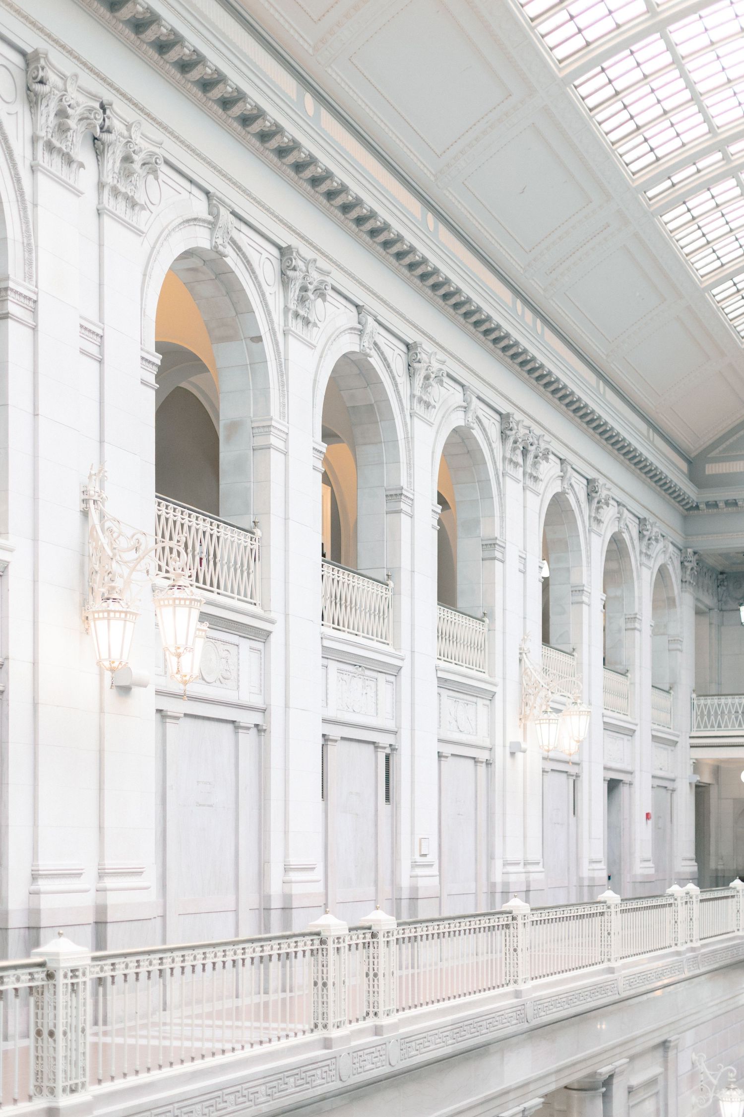 Grand white neoclassical building interior with arched colonnades and skylight.