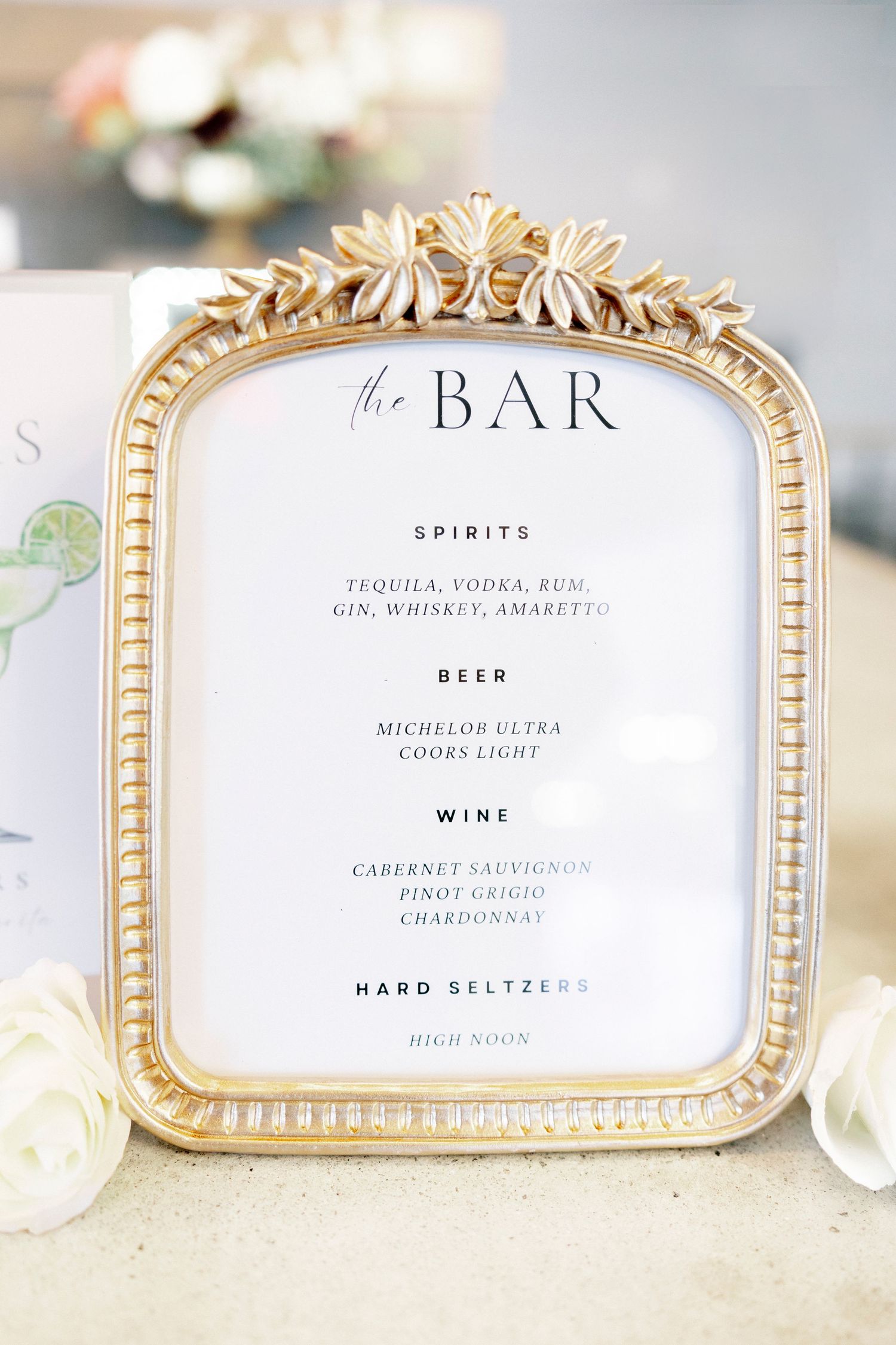Elegant gold ornate framed bar menu sign listing spirits, beer, wine, and hard seltzers for a wedding reception.