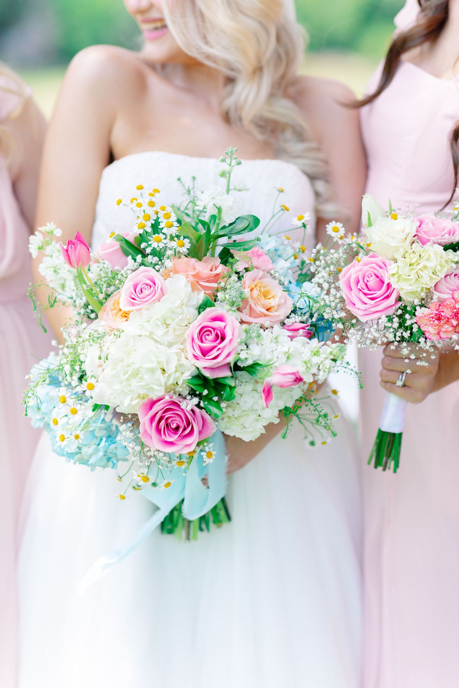 Bride holding a lush spring wedding bouquet with pink roses, tulips, daisies, and hydrangeas, flanked by bridesmaids in pink, Florida