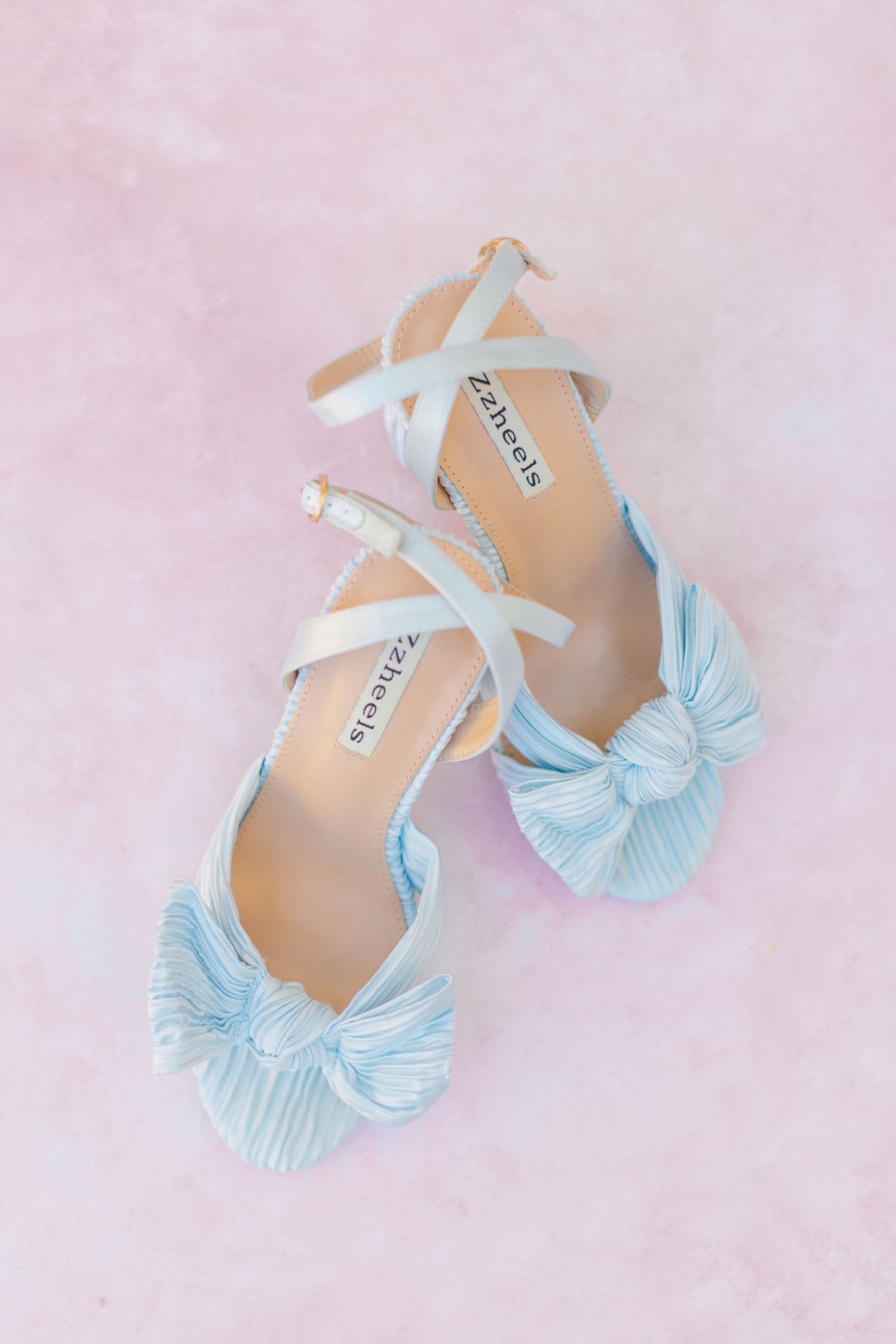 Light blue pleated bow heels with white ankle straps by Z4heels displayed on a pink background, at Bella Cosa