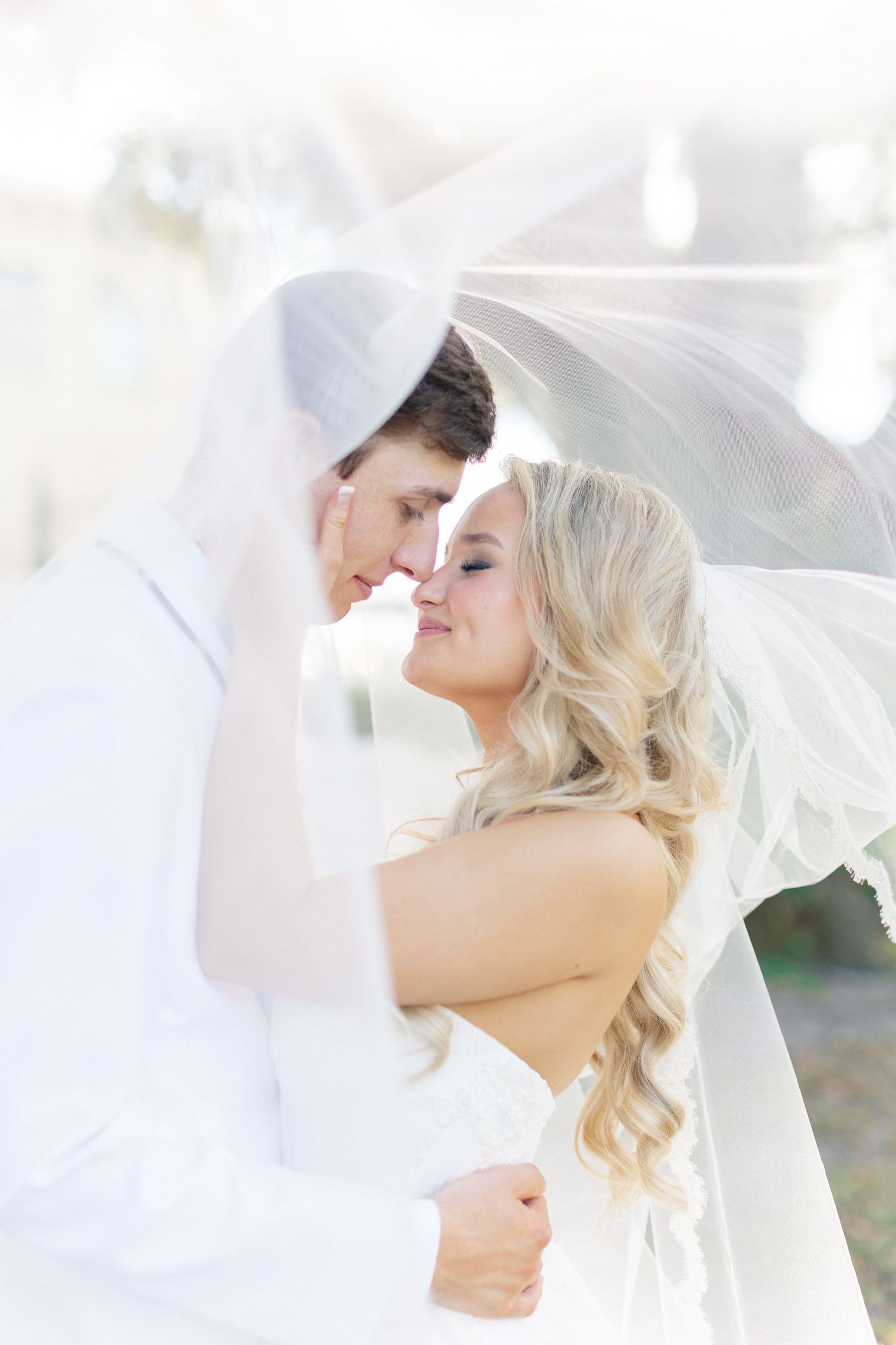 Bride and groom sharing an intimate moment under a flowing white veil on their wedding day, wedding at Bella Cosa
