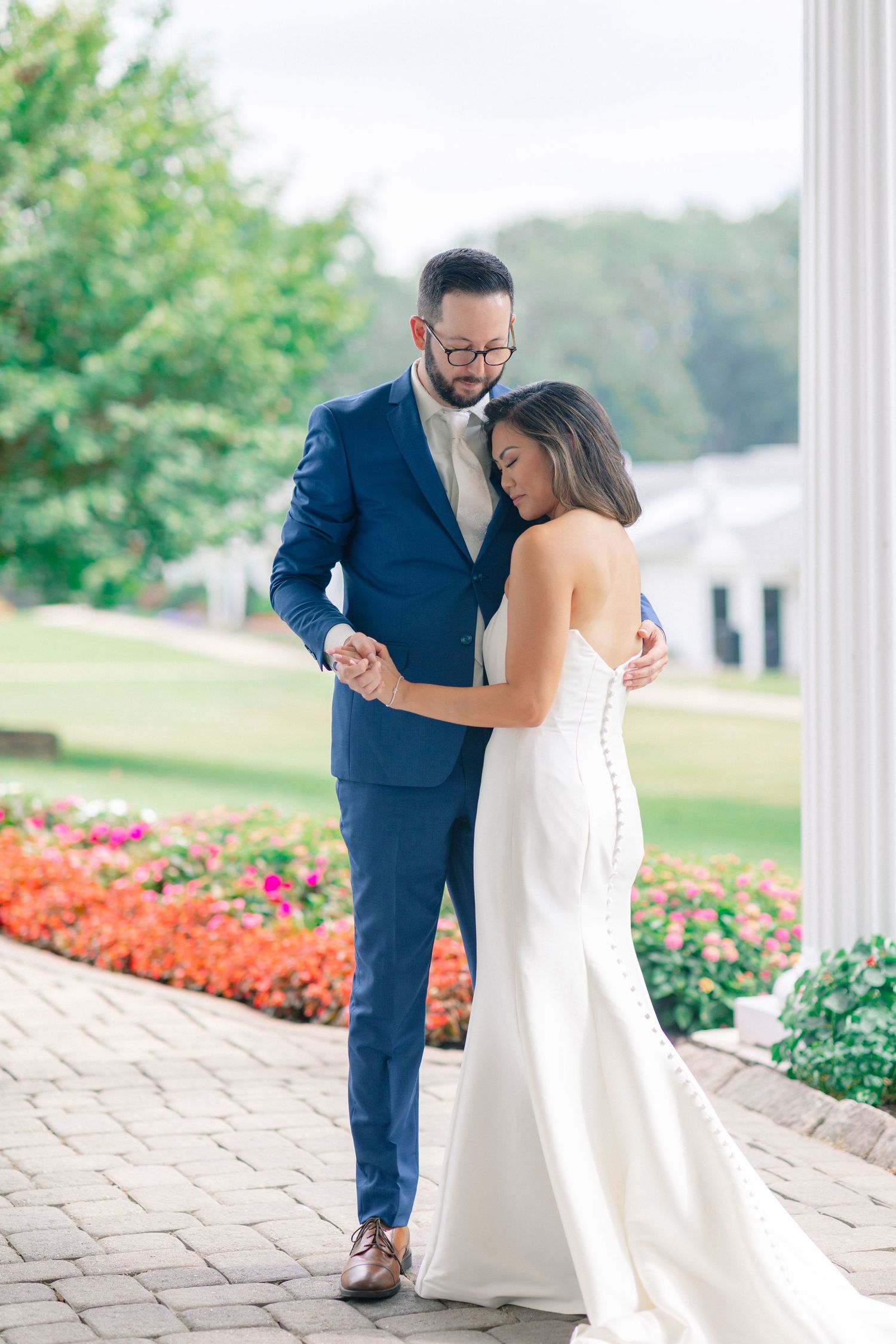Bride and groom share a tender first look moment outdoors, surrounded by colorful flowers and lush greenery.