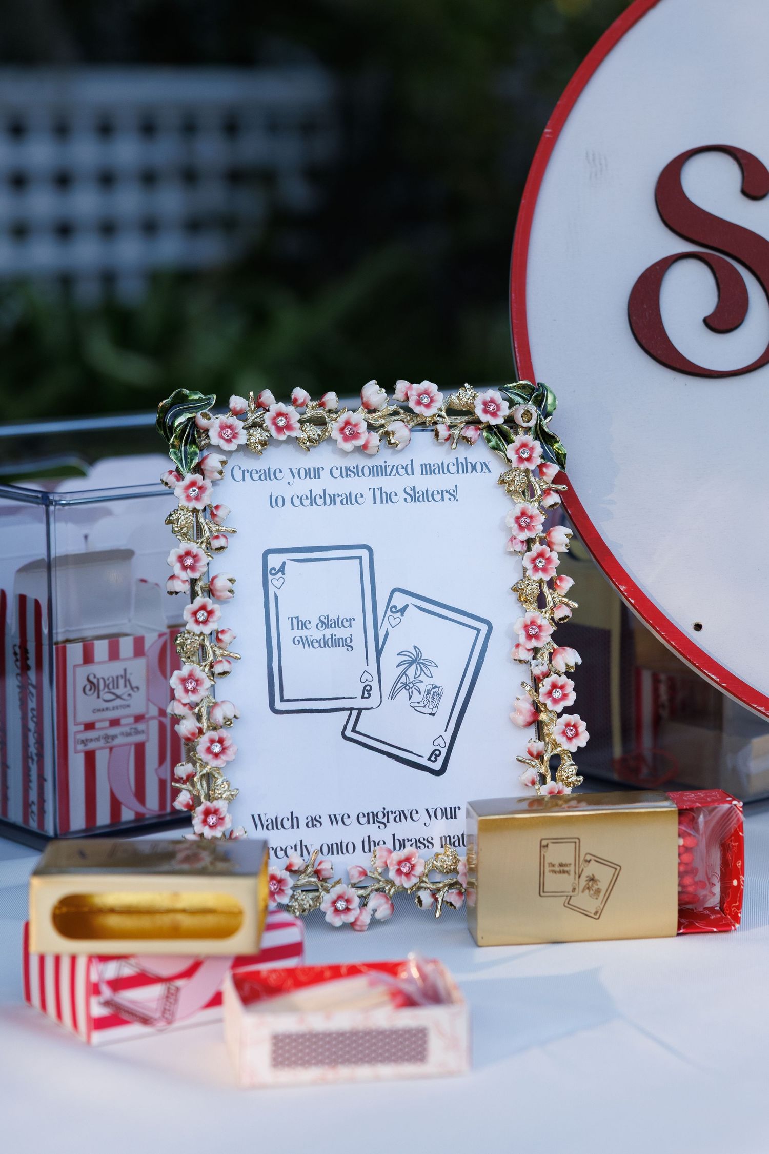 Custom wedding matchbox engraving station with floral frame sign and red striped matchboxes at The Slater Wedding.