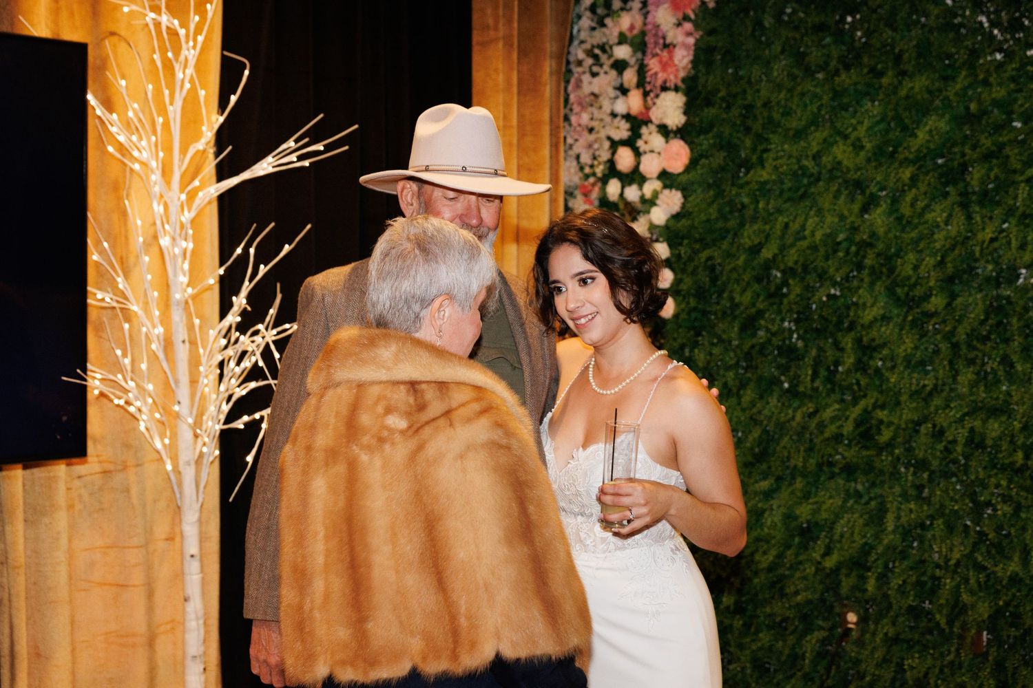 Bride in white gown chatting with guests at outdoor wedding reception.