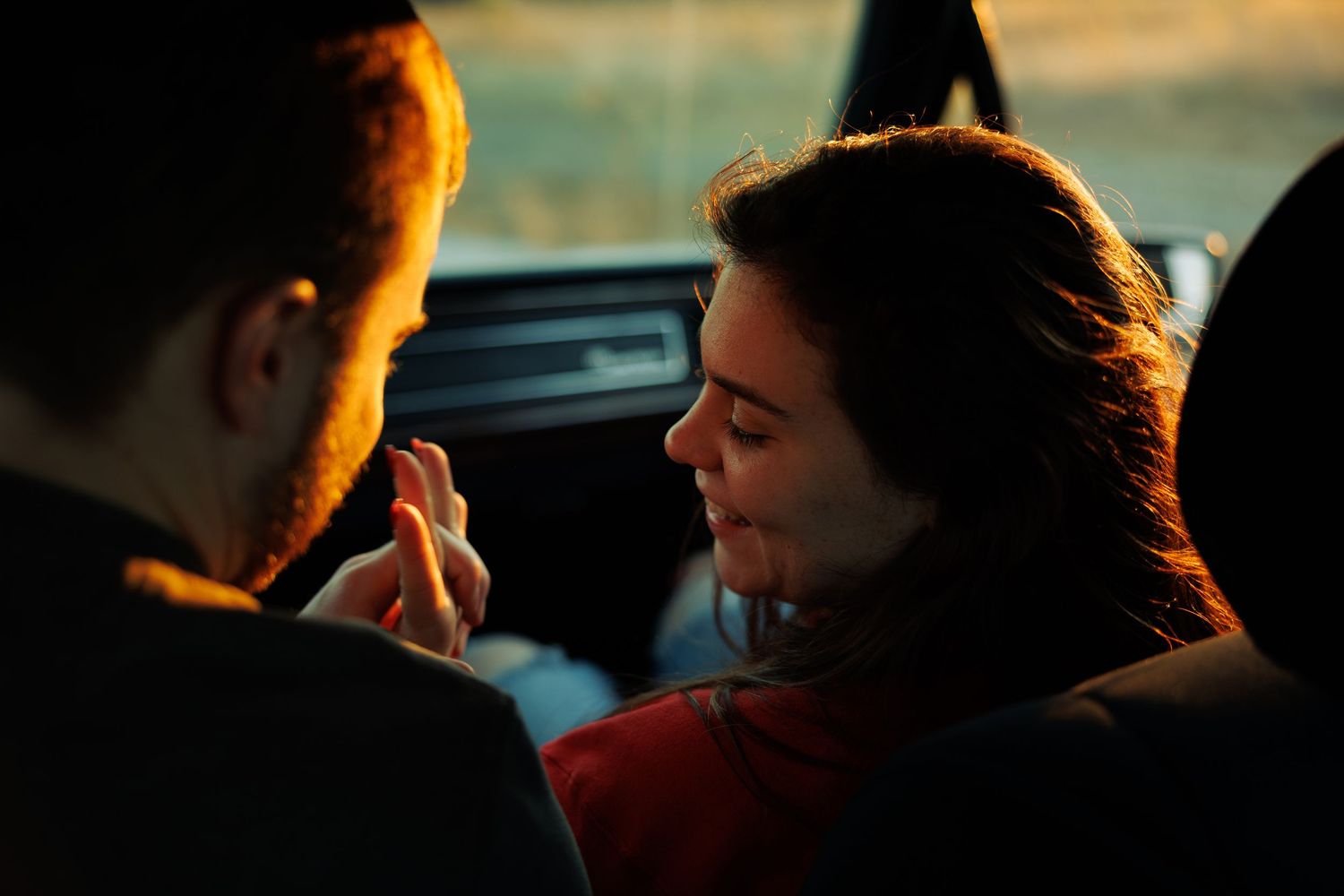 Romantic couple sharing an intimate moment inside a car bathed in warm golden sunset light.