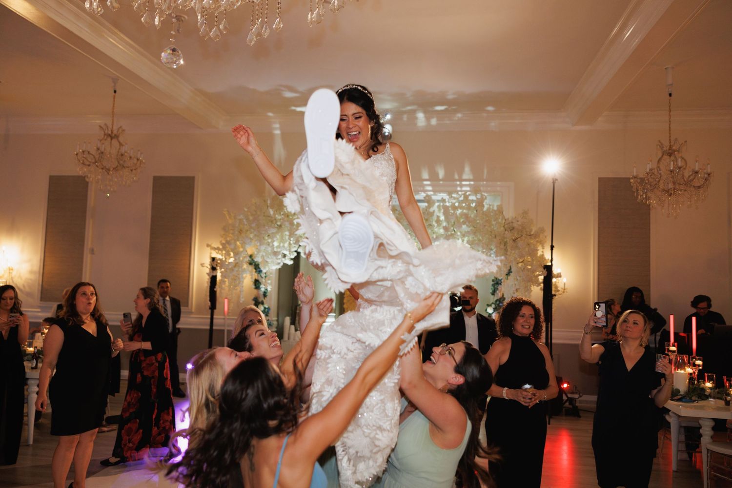 Bride in white gown is lifted by bridesmaids on the dance floor during a wedding reception at The Yorkmont in Charlotte, North Carolina.