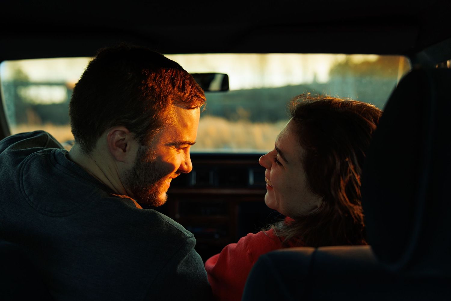 Couple sharing an intimate moment inside a car at sunset.