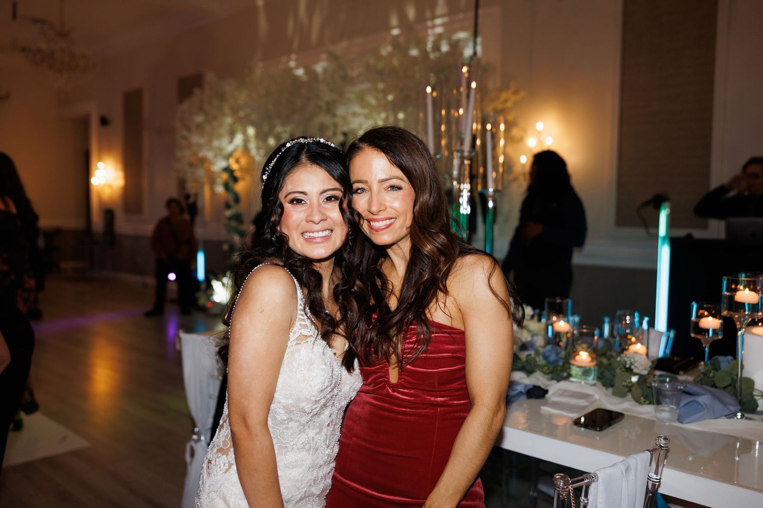 Bride in white gown smiles with a guest in red velvet dress at a elegant wedding reception at The Yorkmont in Charlotte, North Carolina.