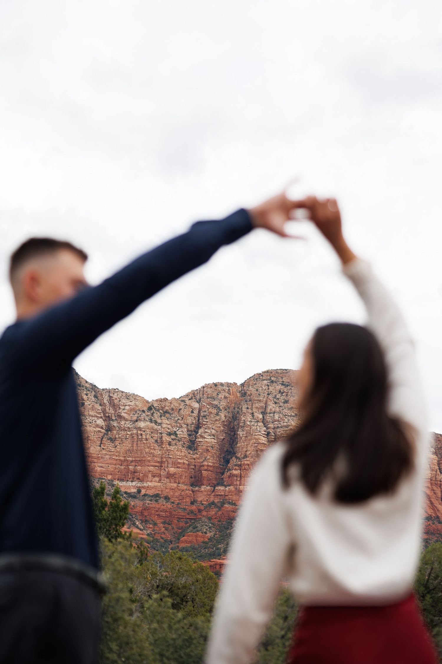 Couple dancing holding hands up with Sedona Arizona red rock mountains in the background.