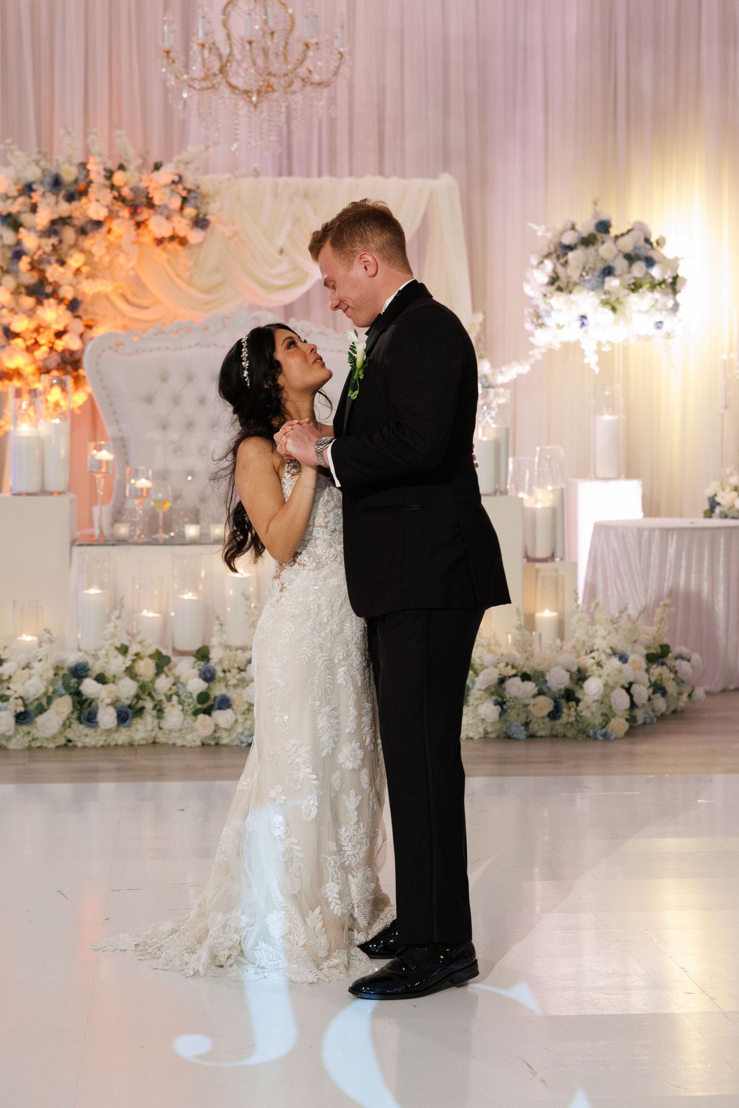 Bride and groom share their first dance in a romantic candlelit ballroom adorned with white floral arrangements at The Yorkmont in Charlotte