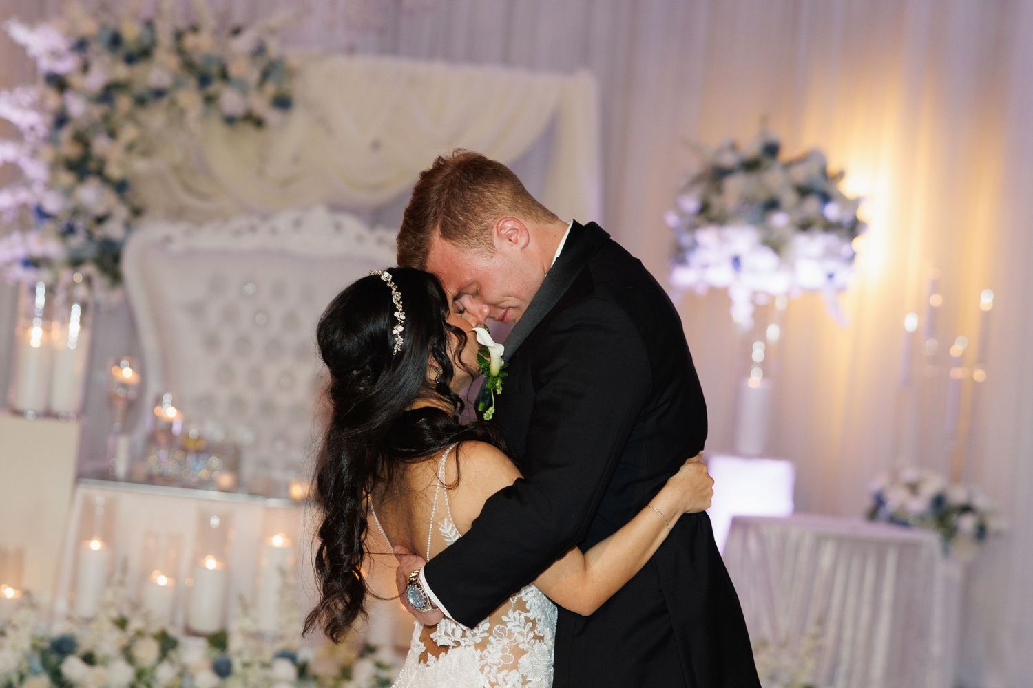 Bride and groom share their first dance surrounded by candles and floral arrangements at an elegant wedding reception.