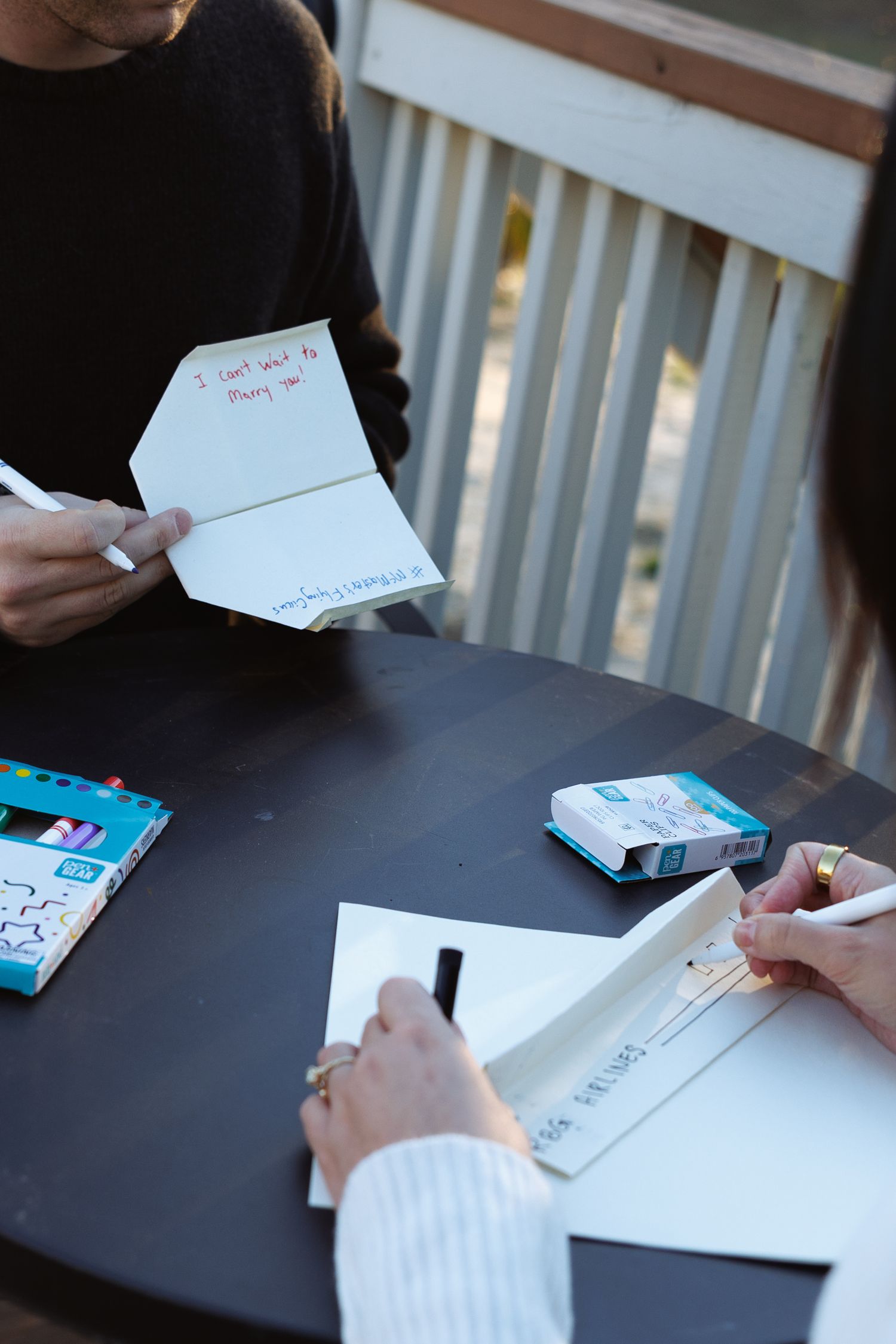 Close-up of couple reading and writing heartfelt greeting cards at an outdoor table.
