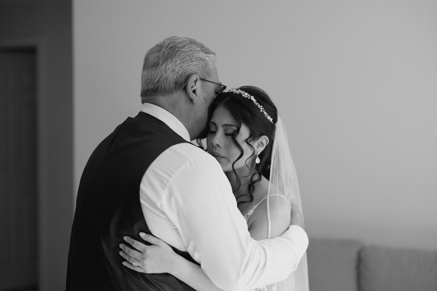 Black and white photo of a bride and older man sharing an emotional embrace on her wedding day.