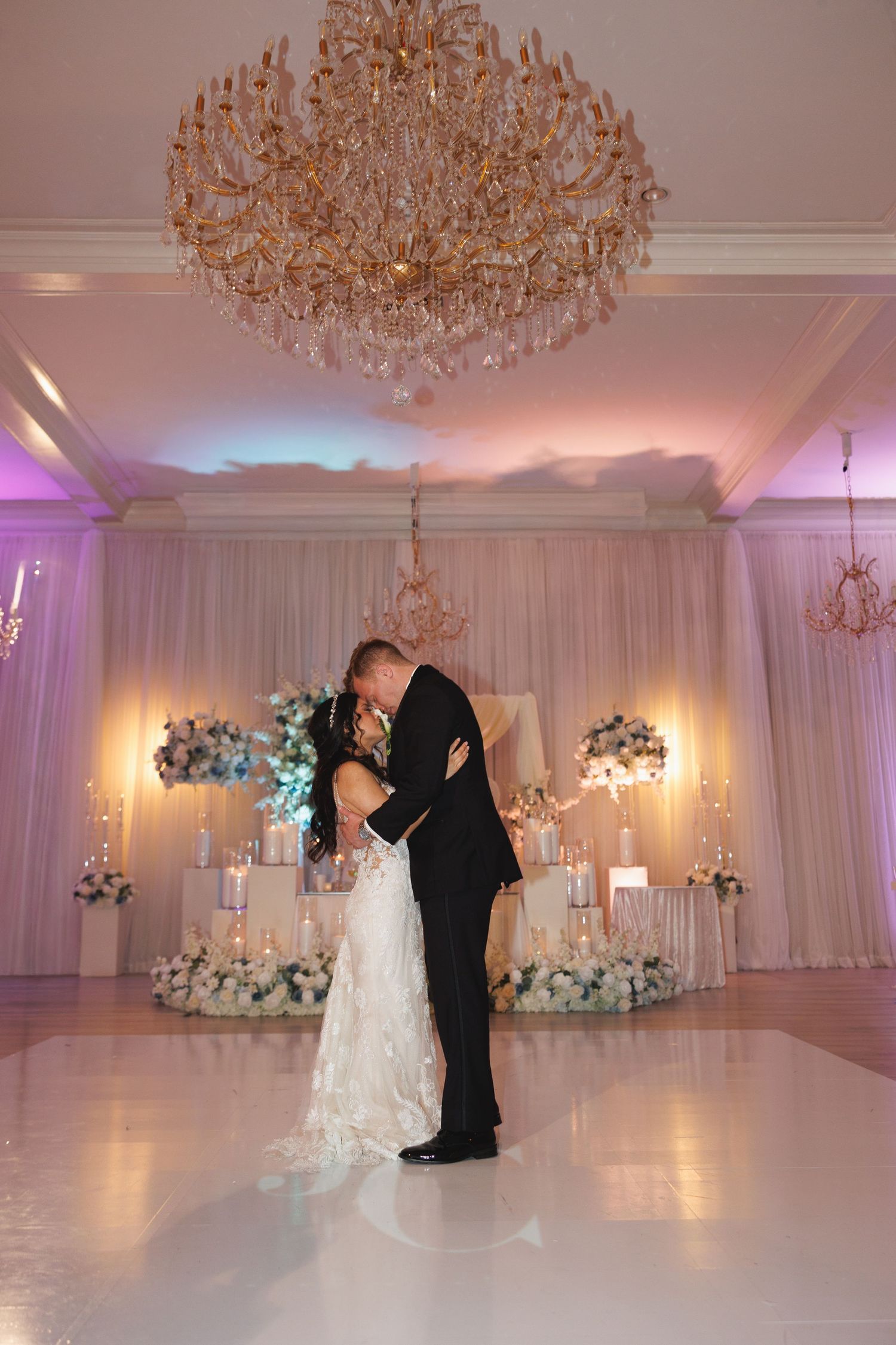Bride and groom share a romantic kiss on the dance floor beneath a gold crystal chandelier at wedding at The Yorkmont in Charlotte, NC.