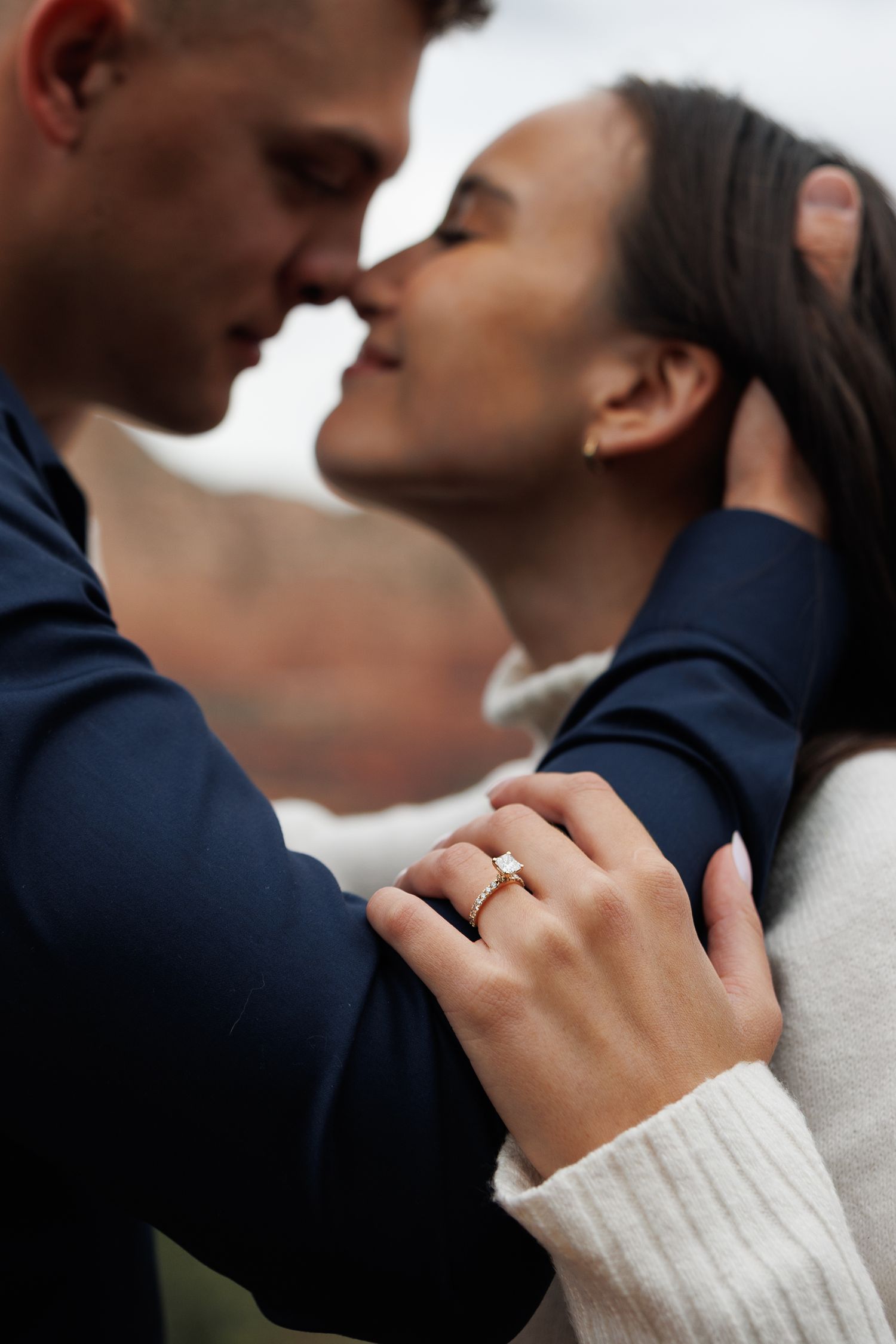 Close-up of couple about to kiss showing diamond engagement ring on womans hand.