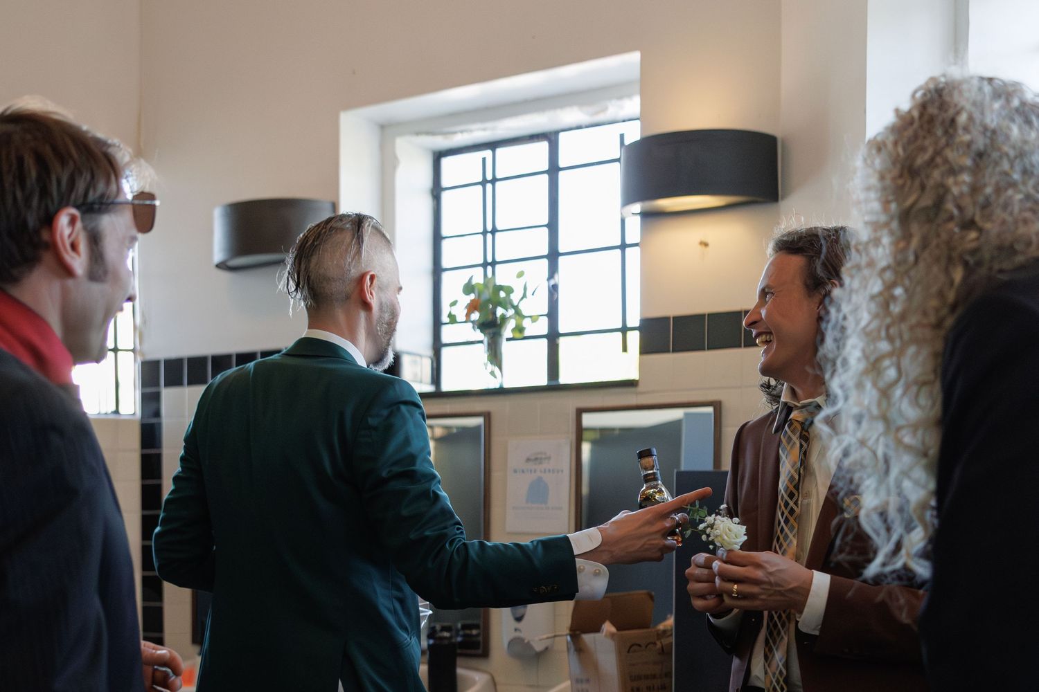 Guests in formal attire socializing and clinking glasses at an indoor wedding cocktail reception.