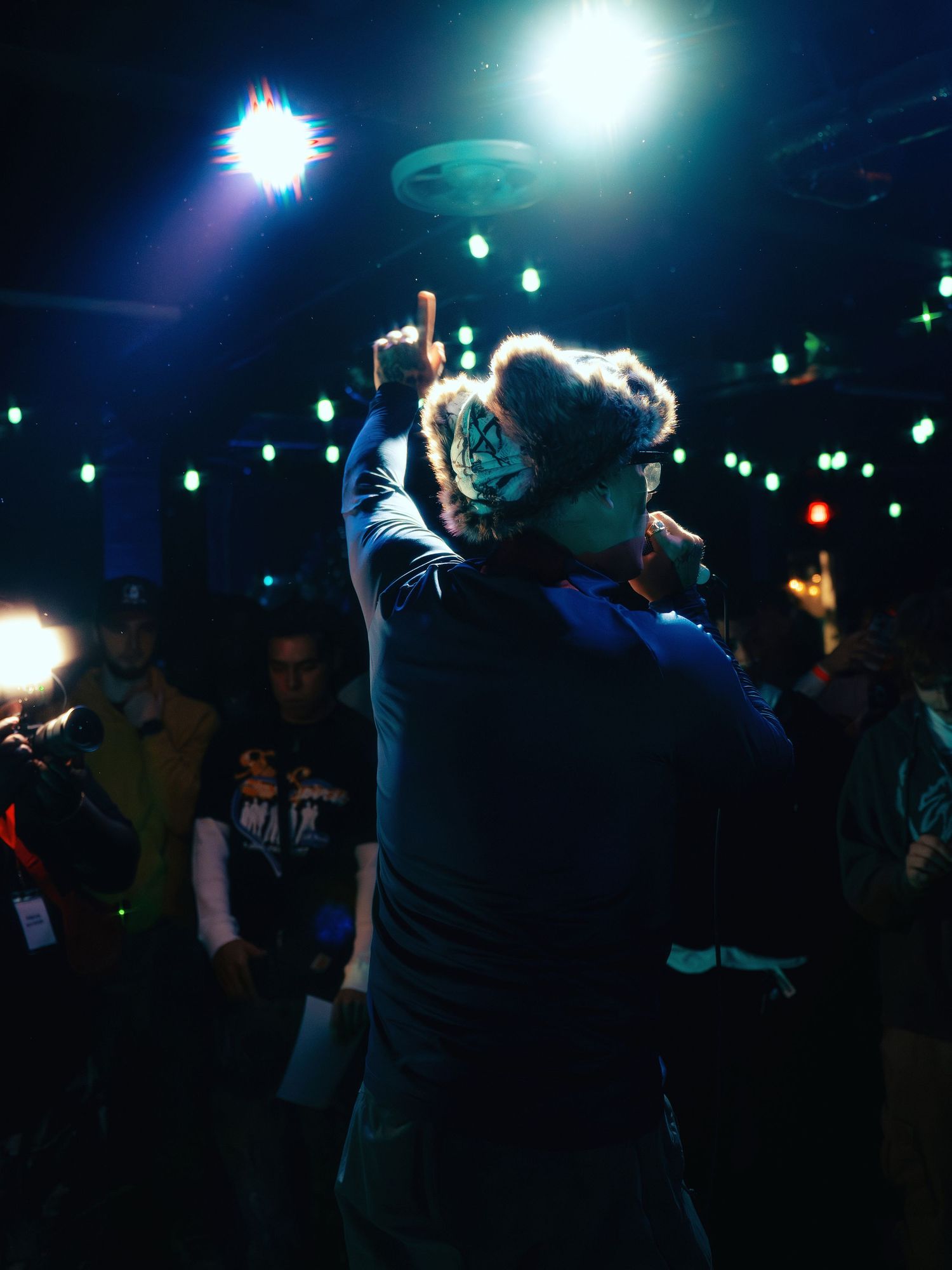Nighttime concert scene with crowd silhouettes against blue spotlights.