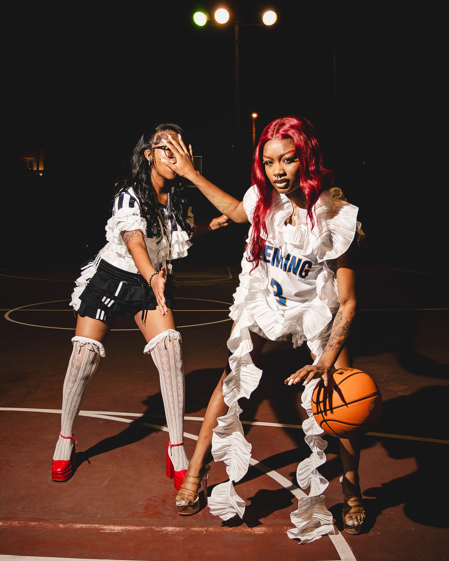 Dynamic basketball players in white uniforms practicing dribbling moves on dark court.