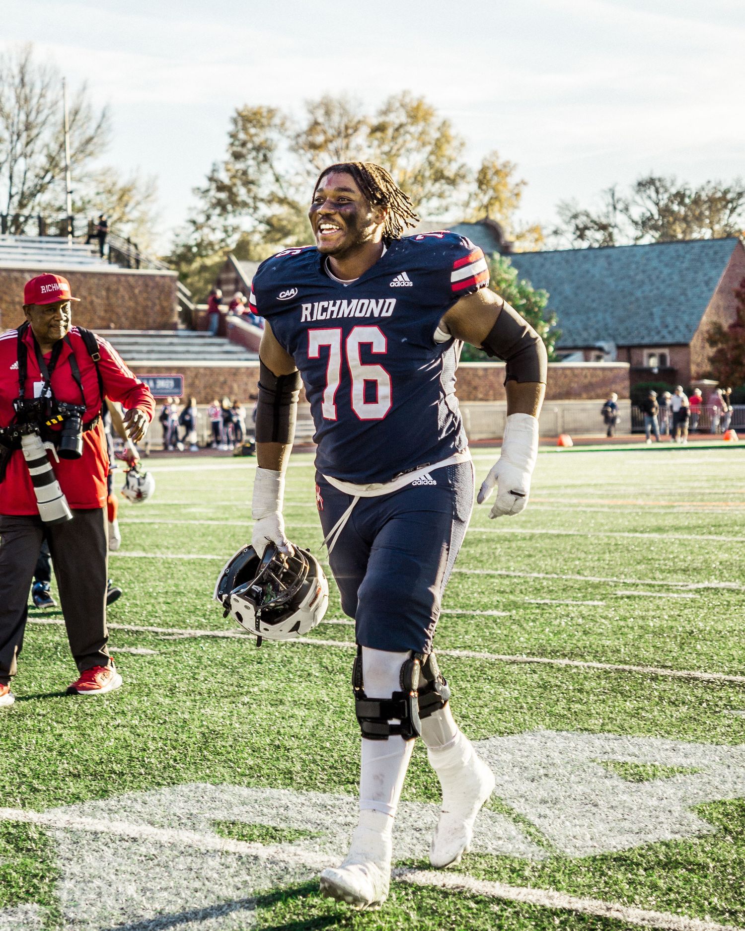 Football player in navy uniform number 76 celebrates on the field.