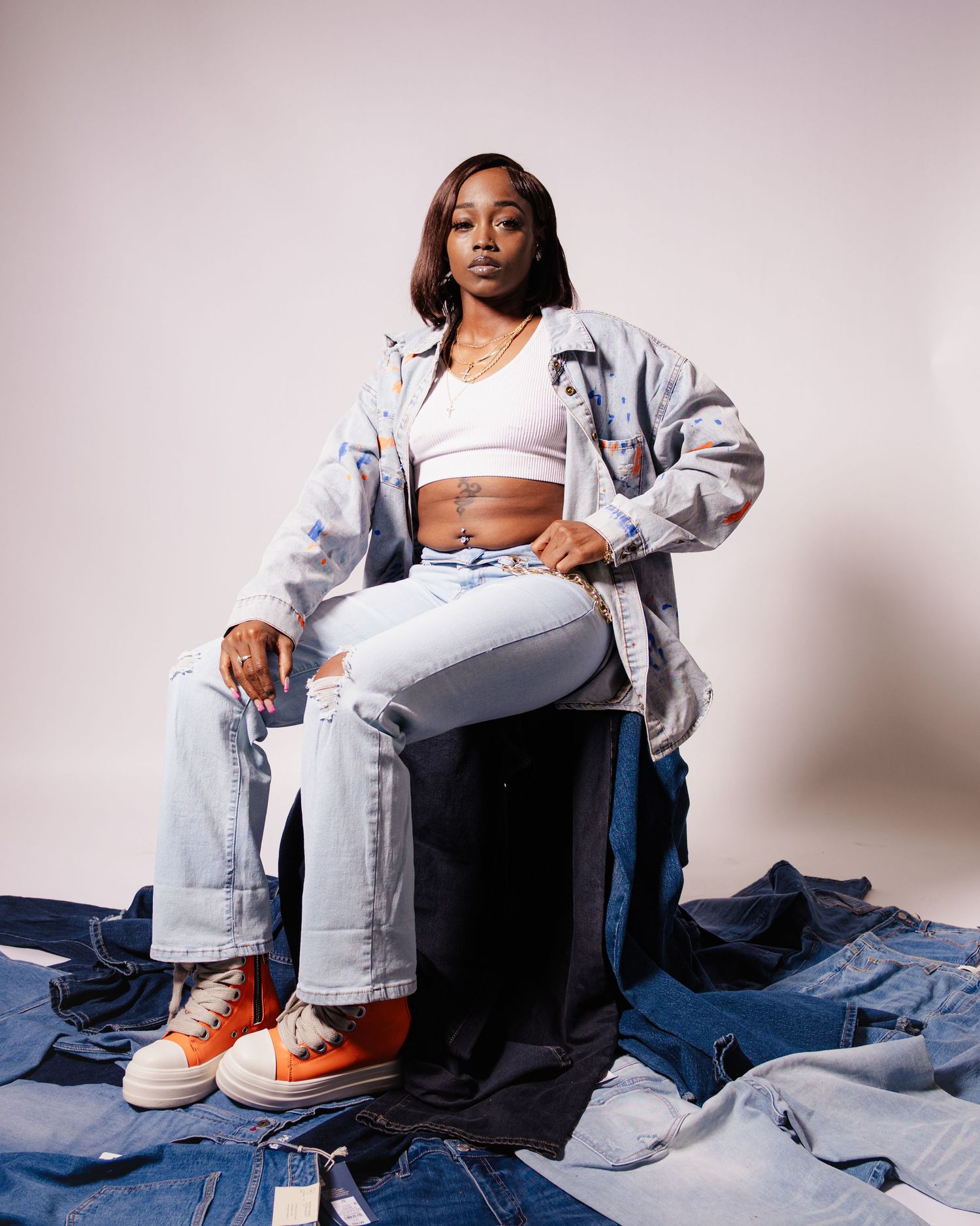 Casual fashion photoshoot featuring denim outfits and orange sneakers against a light studio background.