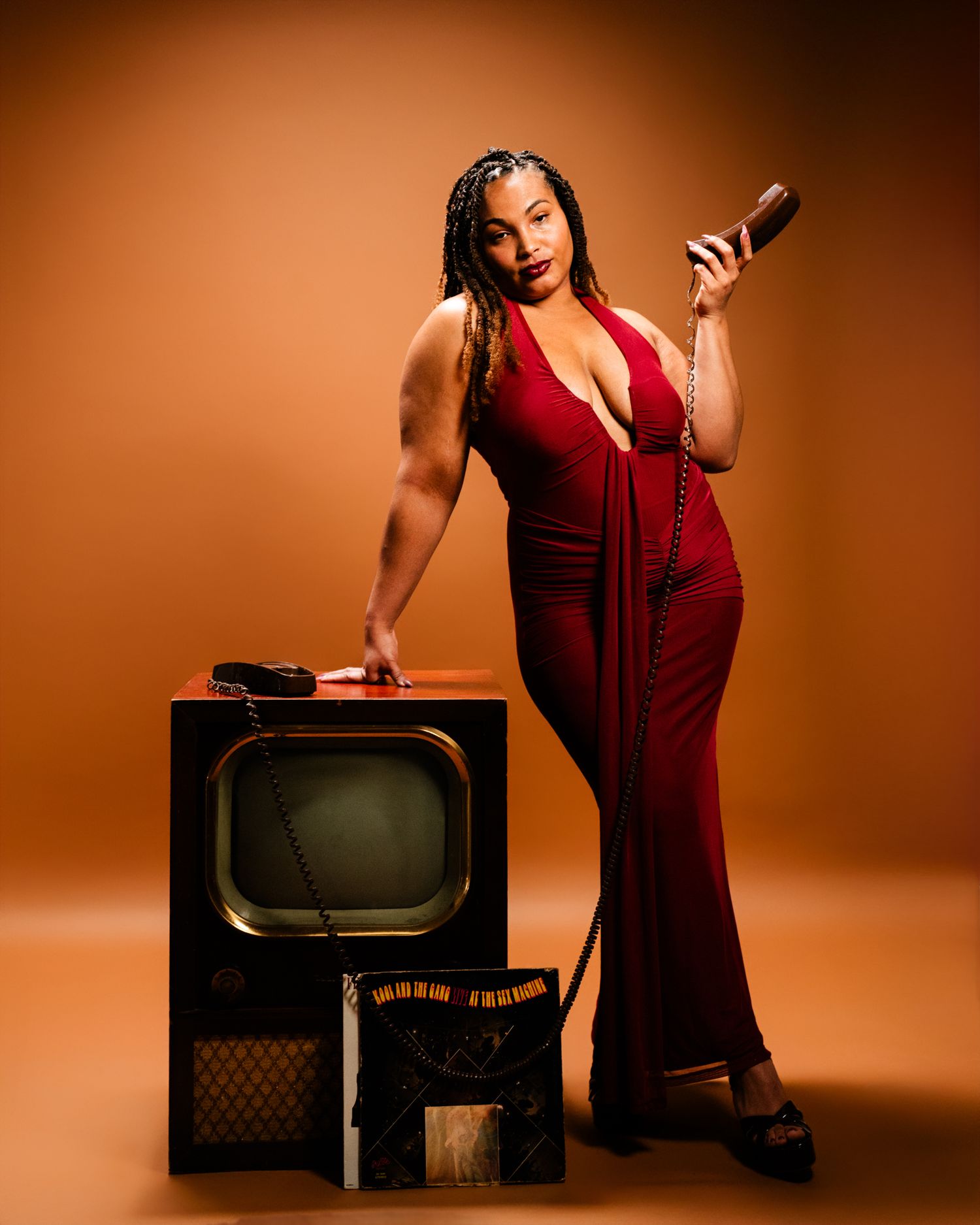 Vintage-inspired photoshoot with retro television props against warm brown background.