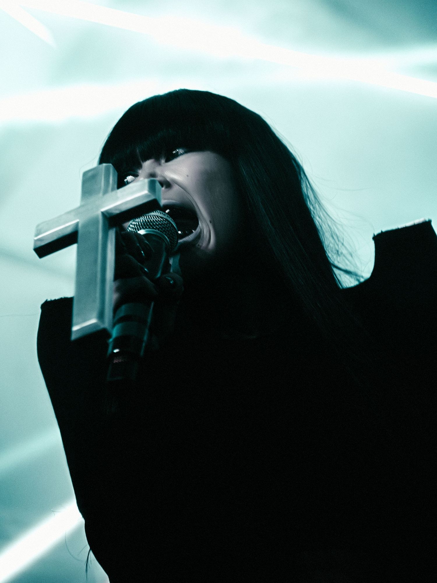 Silhouetted figure using camera equipment against blue-tinted background.