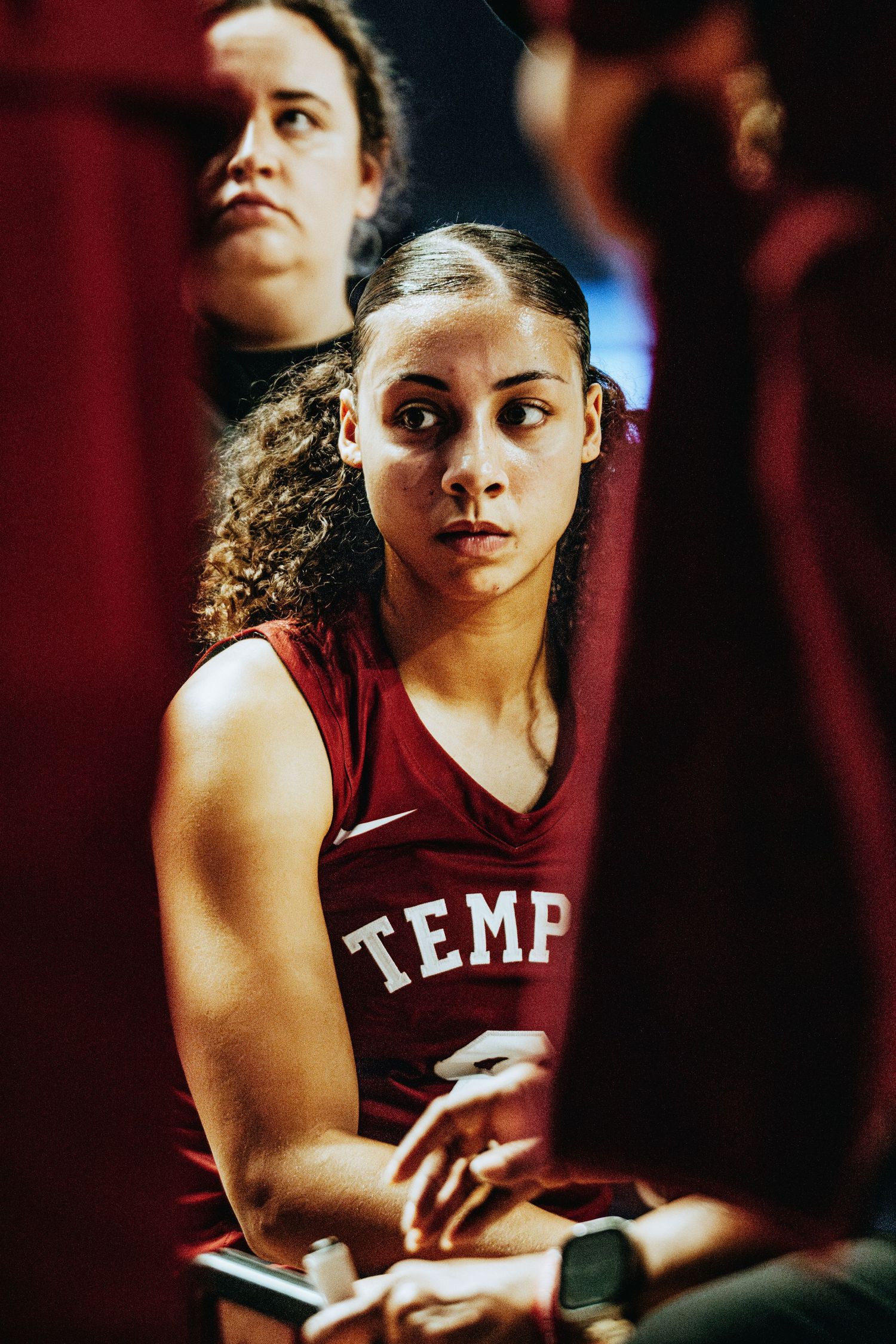 Basketball player in a Temple jersey sits focused during a game.