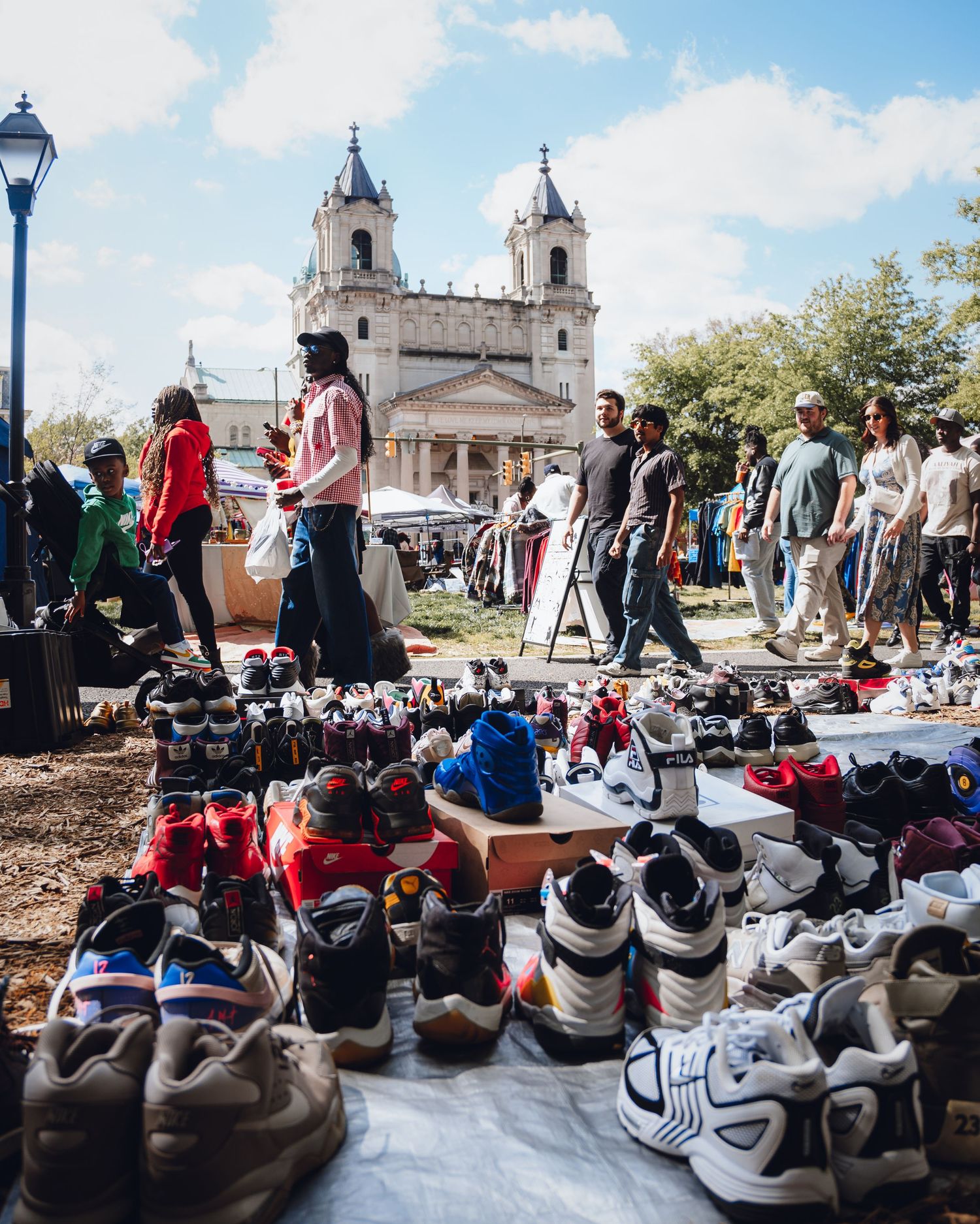 Row of athletic shoes lined up at an outdoor event with a church in the background.