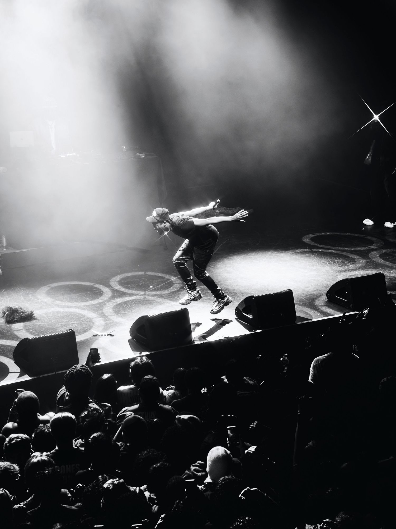 Concert performer silhouetted on stage with dramatic lighting and fog effects.