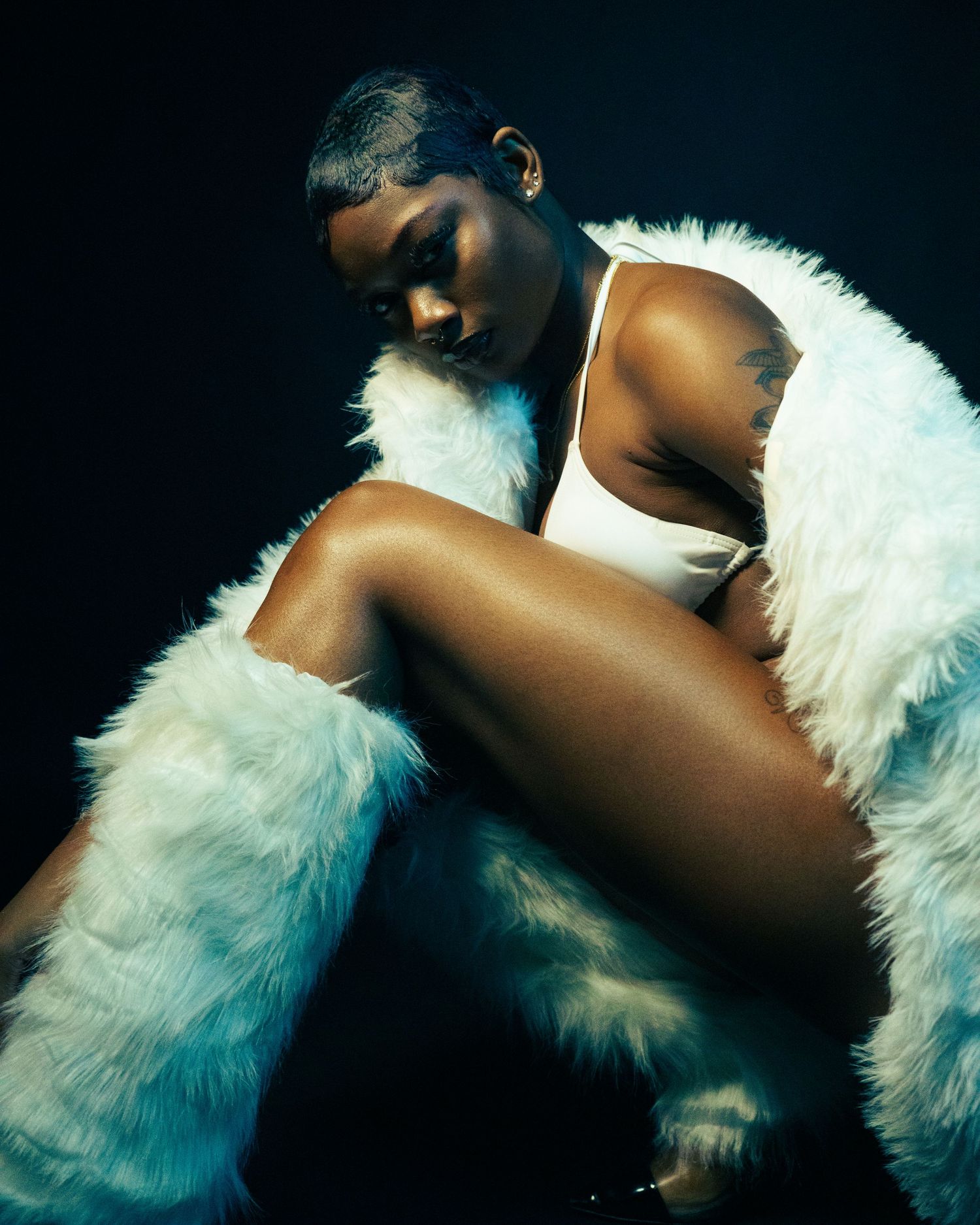 Artistic portrait featuring white feathers against dark background in dramatic lighting.