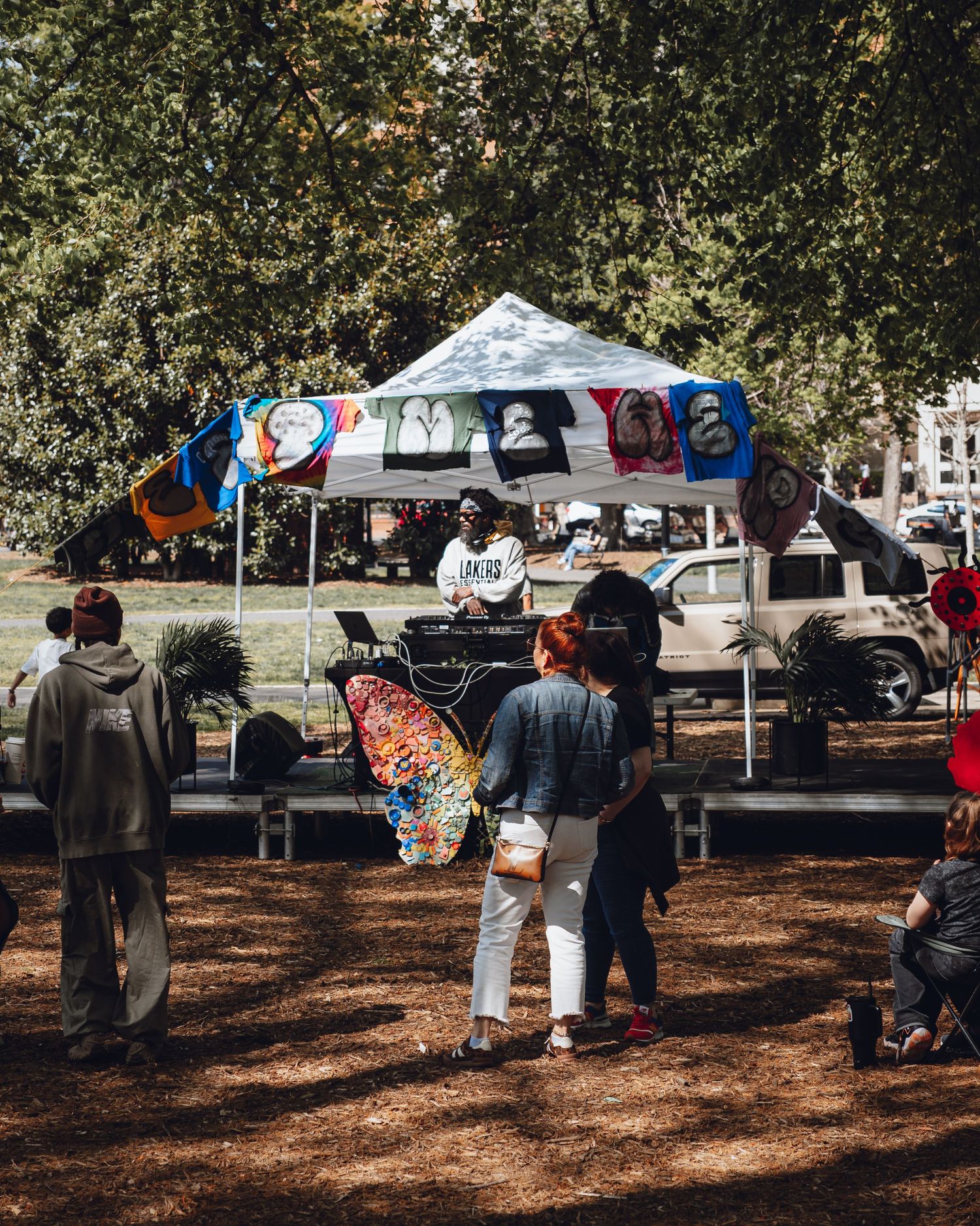 Outdoor market setup with tents and vendors under autumn trees.