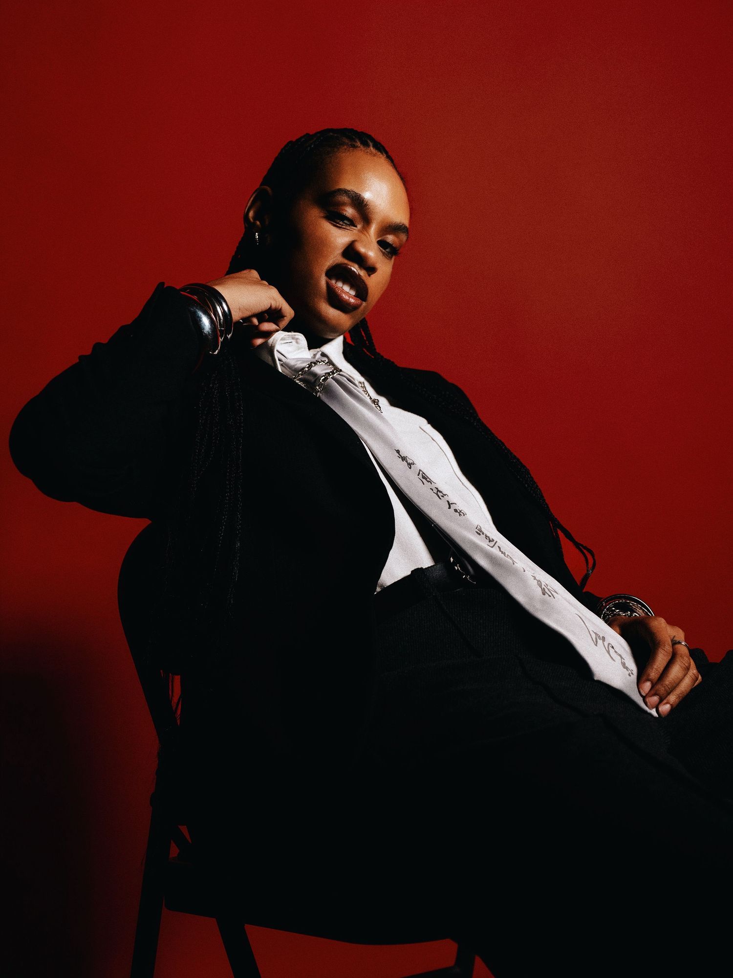 Artistic fashion portrait against vibrant red backdrop featuring black suit and white shirt combination.