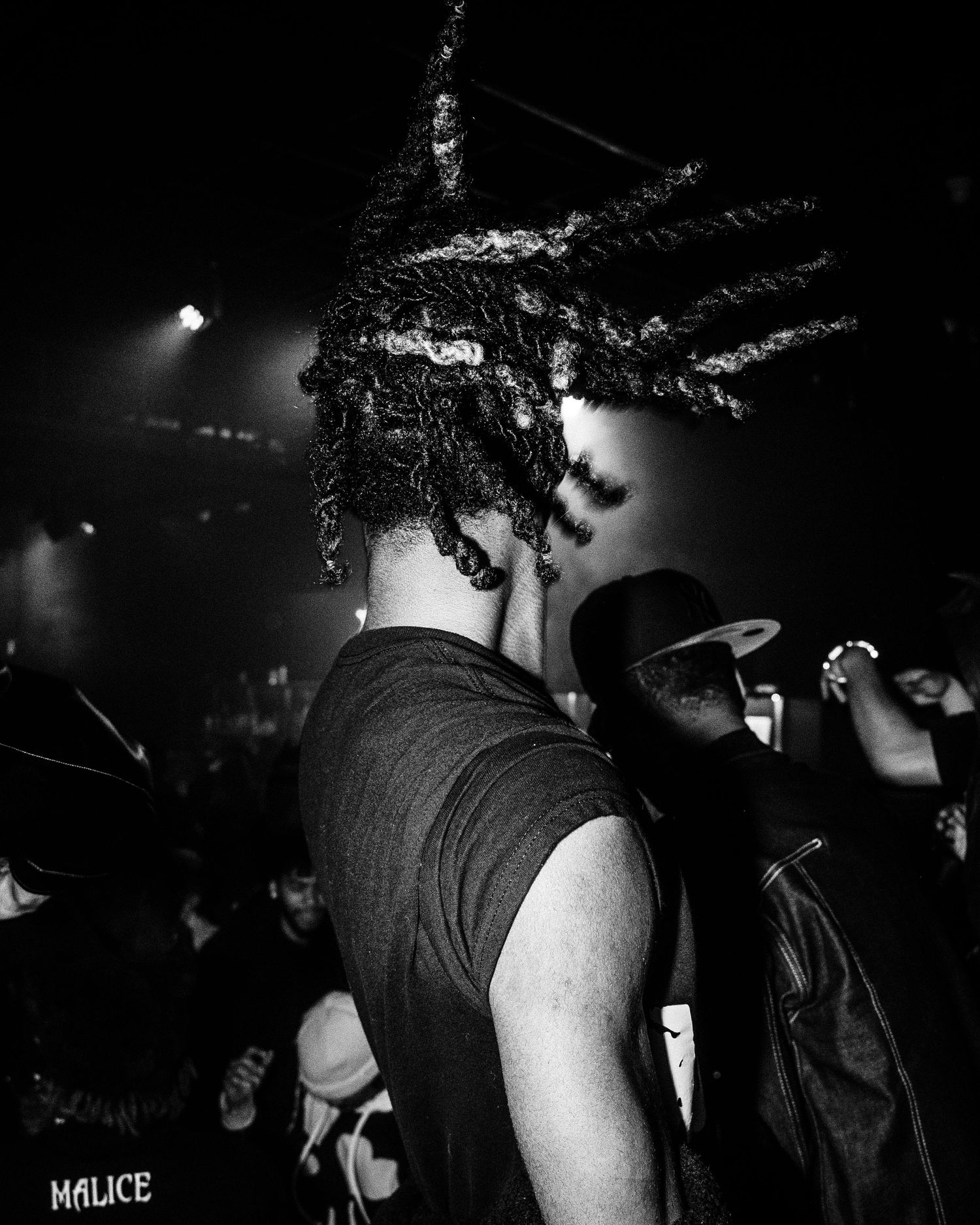 Black and white concert photo showing silhouette with braided hair from behind.
