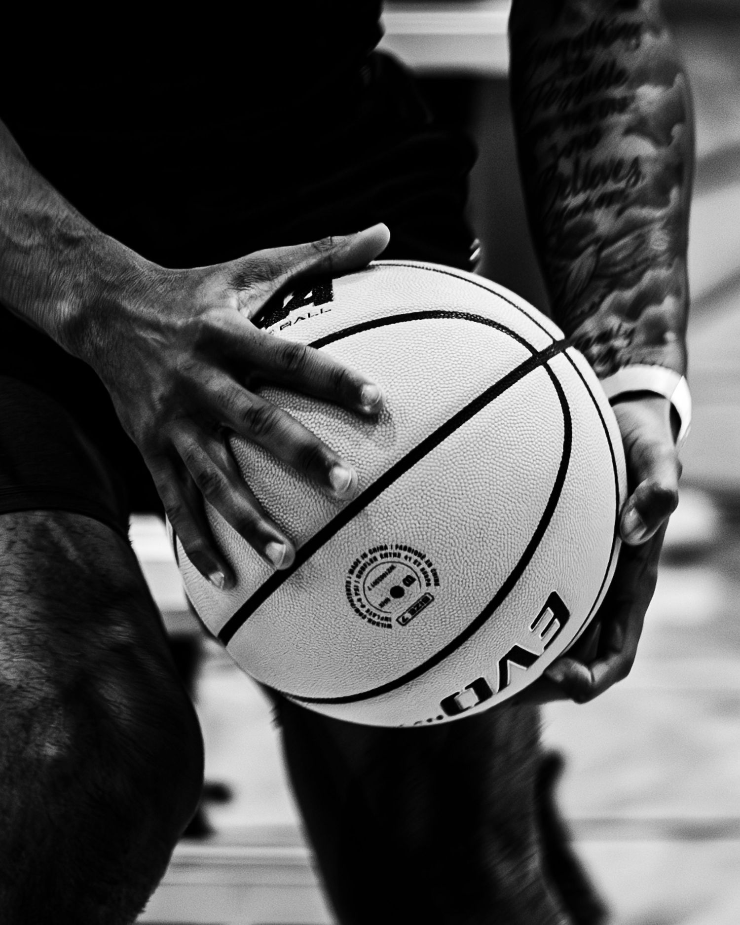 Black and white close-up of hands holding a basketball showing NBA logo.